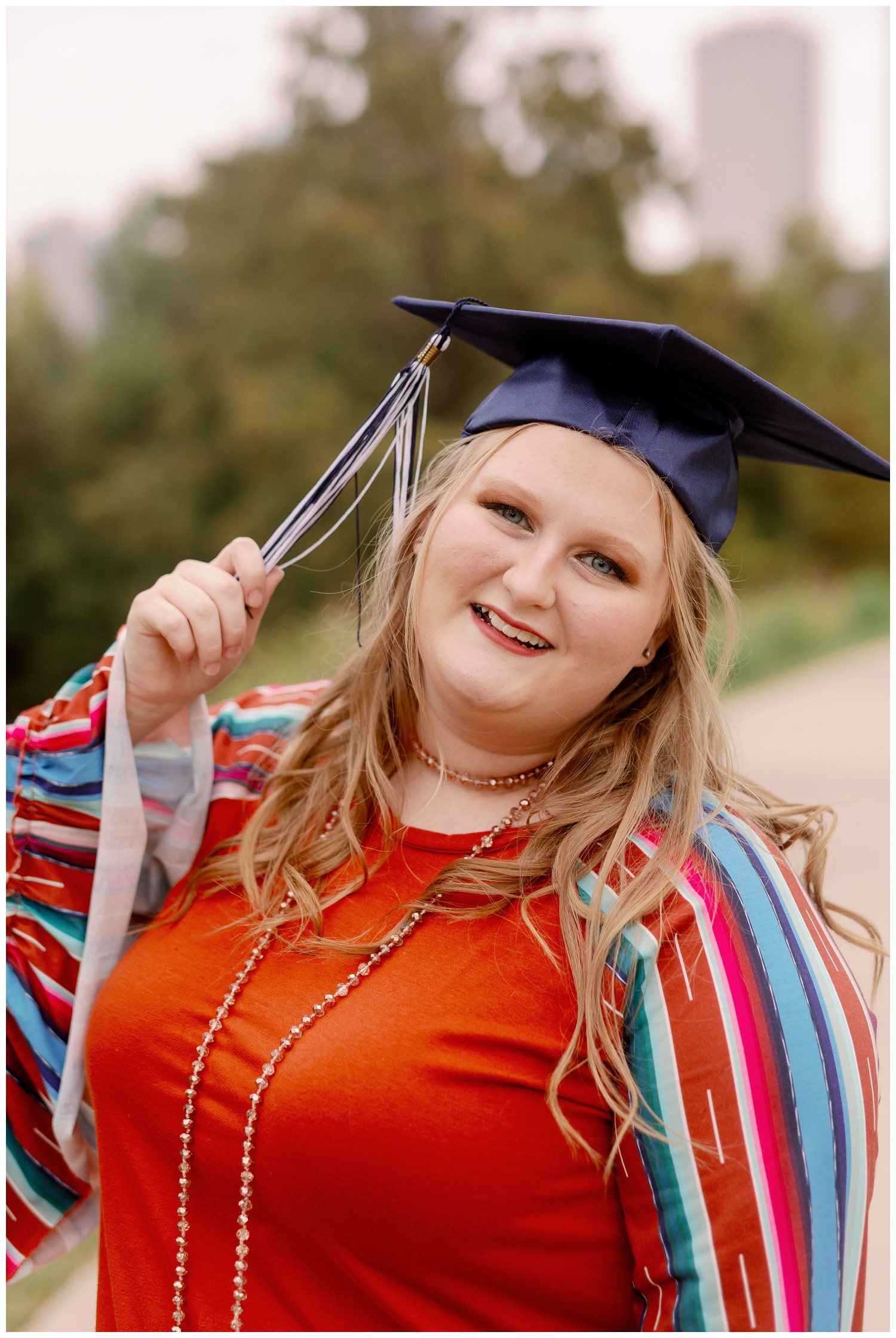 high school senior girl pulling blue and white tassel on graduation cap at Eleanor Tinsley Park