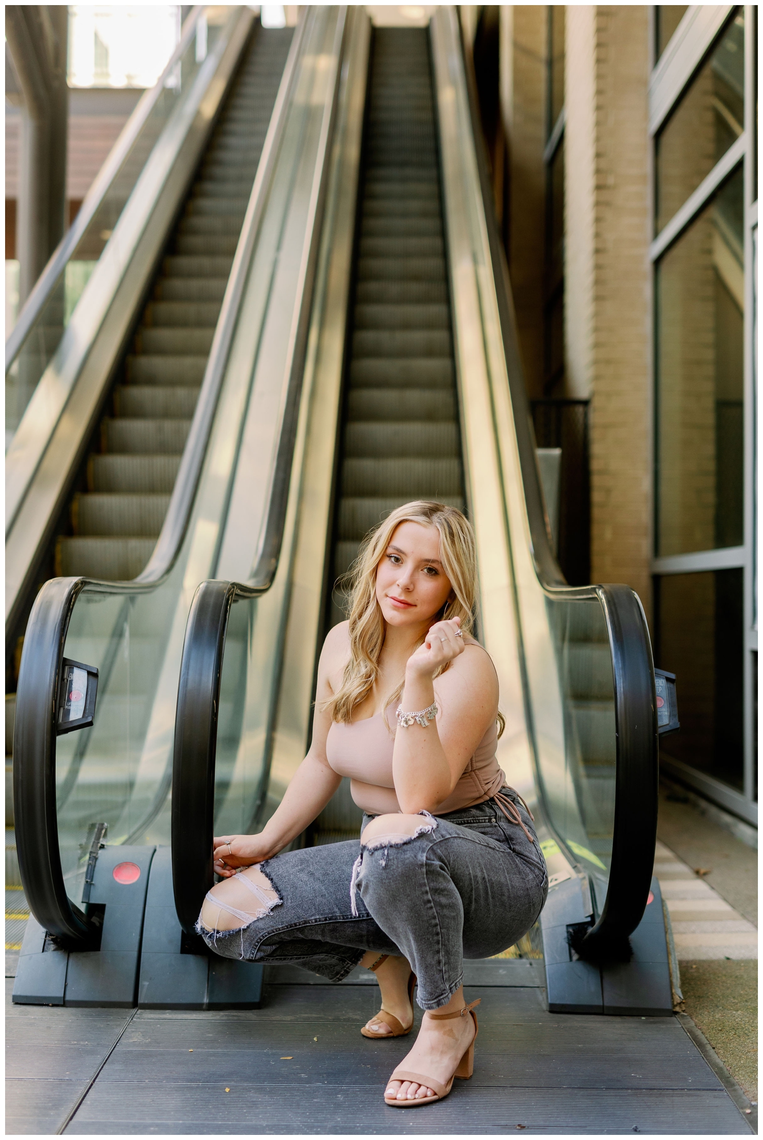 girl squatting in front of escalator for senior photos Main Street Houston, Texas