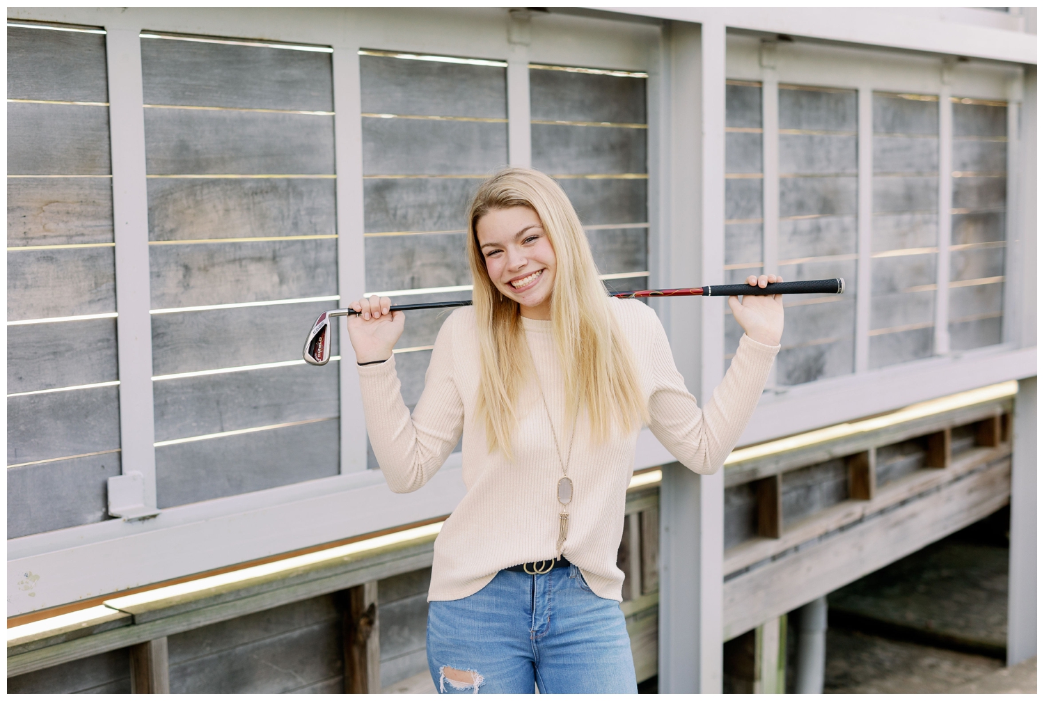 girl in jeans and cream sweater holding golf club