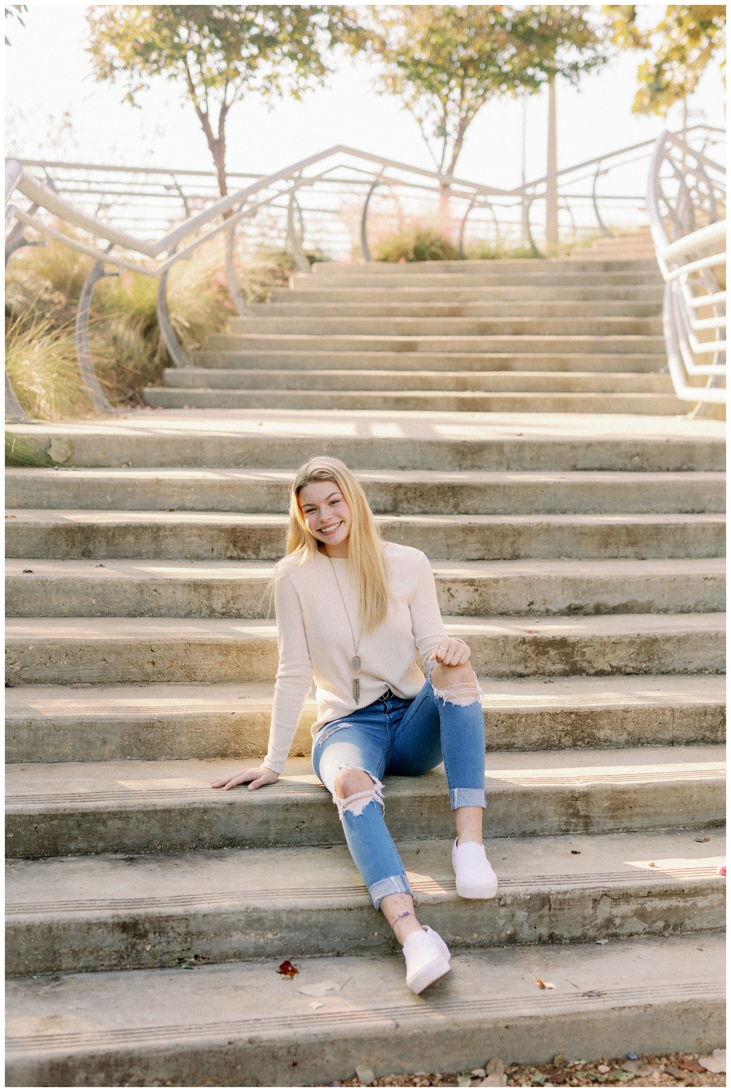 Dawson High school senior in jeans and cream shirt sitting on stairs in downtown Houston