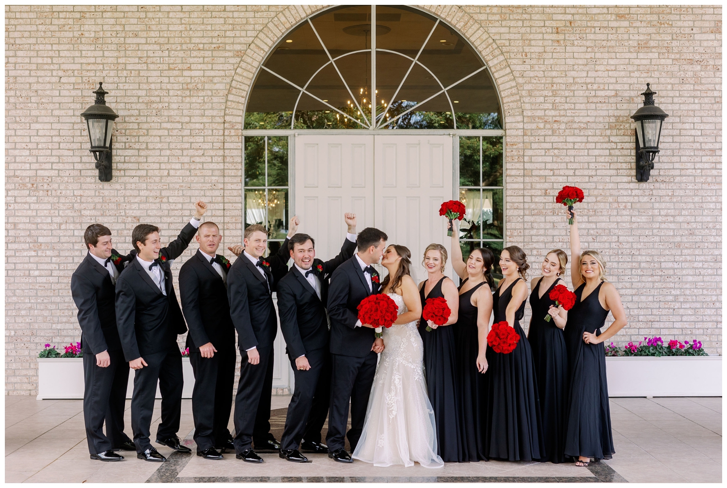 bridal party in black dresses and black tuxes celebrating outside Sugar Creek Country Club wedding