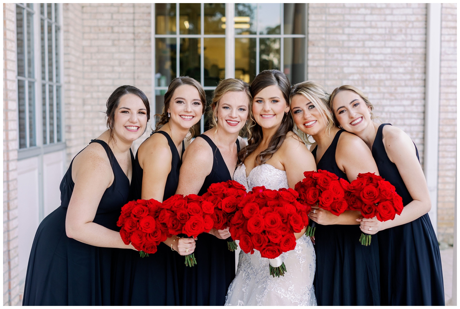 bride and bridesmaids with black dresses and red roses outside Sugar Creek Country Club