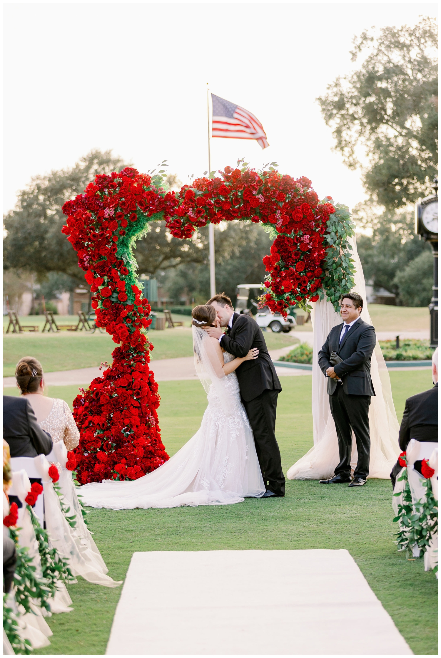bride and groom ceremony kiss in front of red floral arch Sugar Creek Country Club wedding