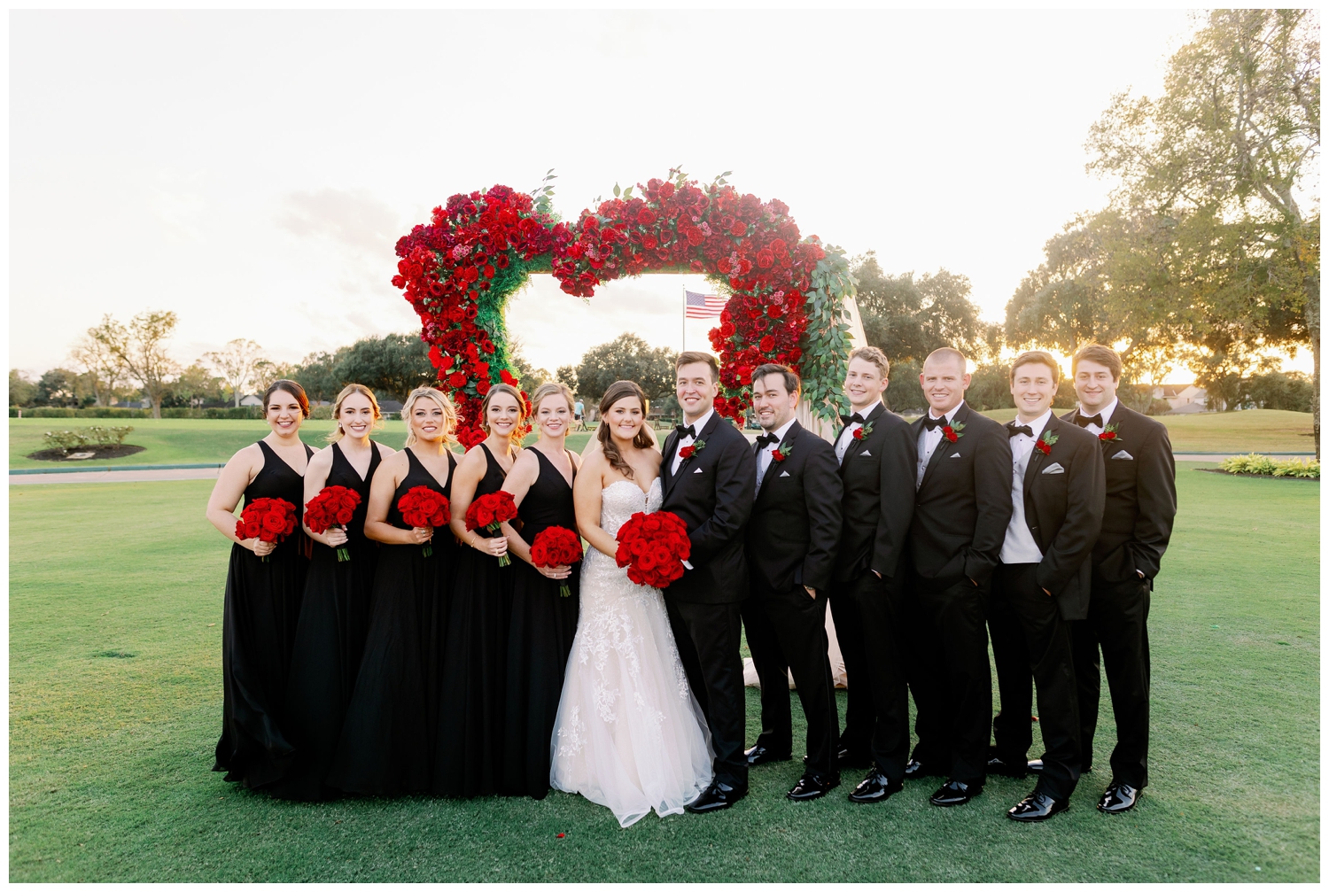 bridal party in front of red rose arch outdoors at Sugar Creek Country Club wedding