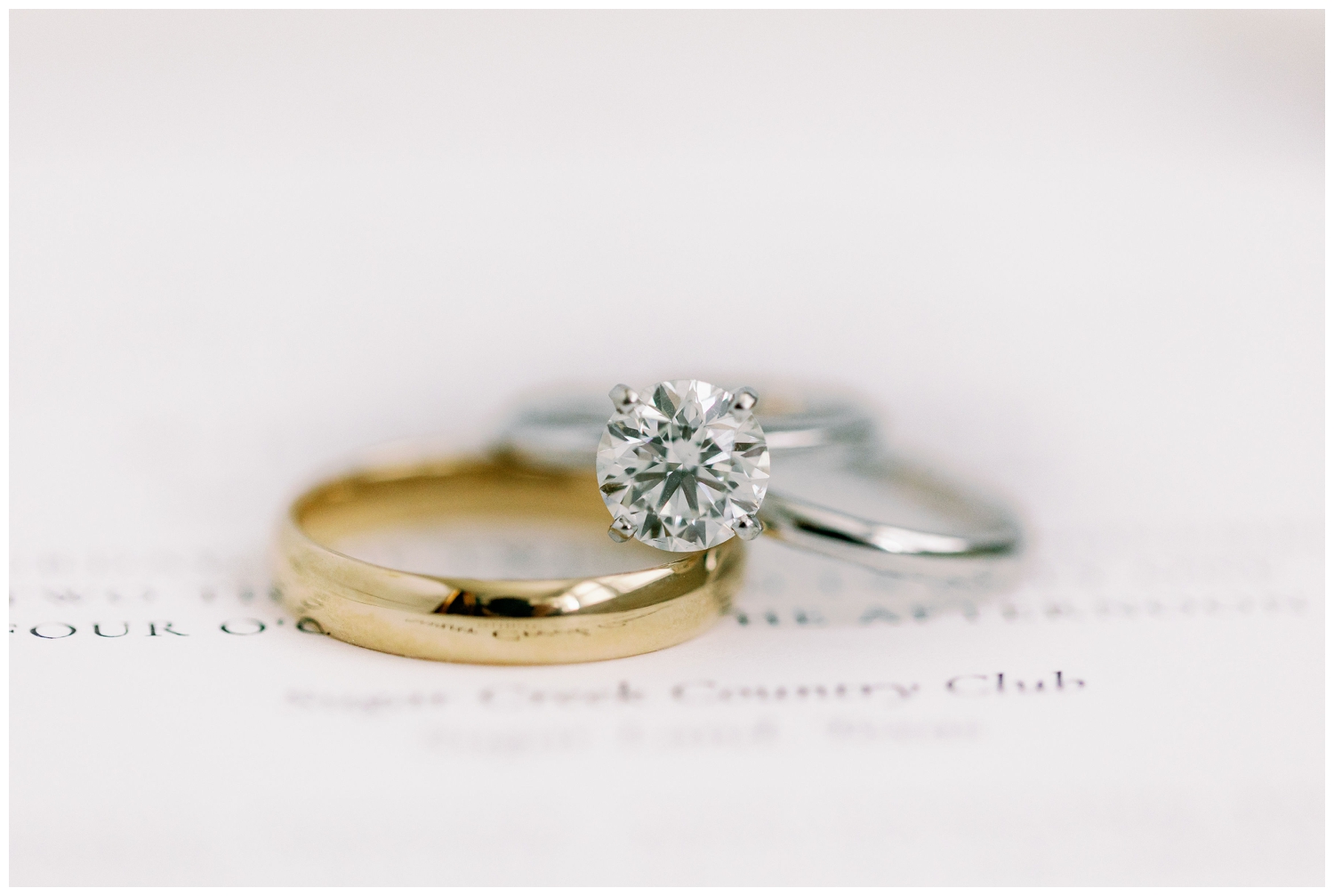 wide image of wedding rings on top of white invitation