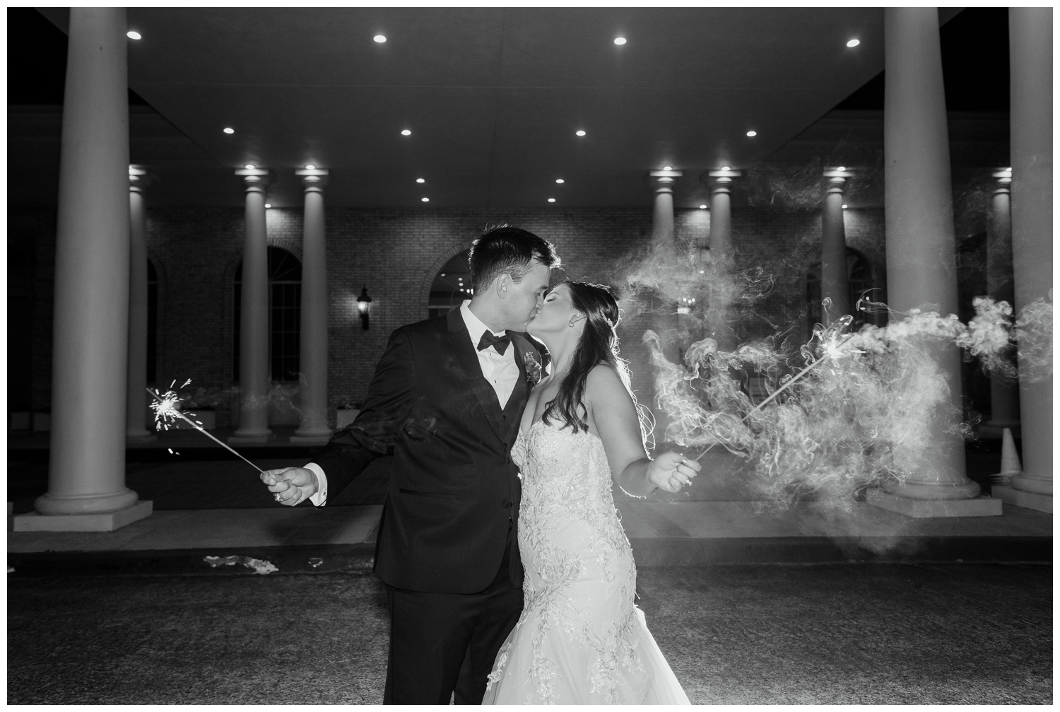 black and white portrait of bride and groom kissing with sparklers