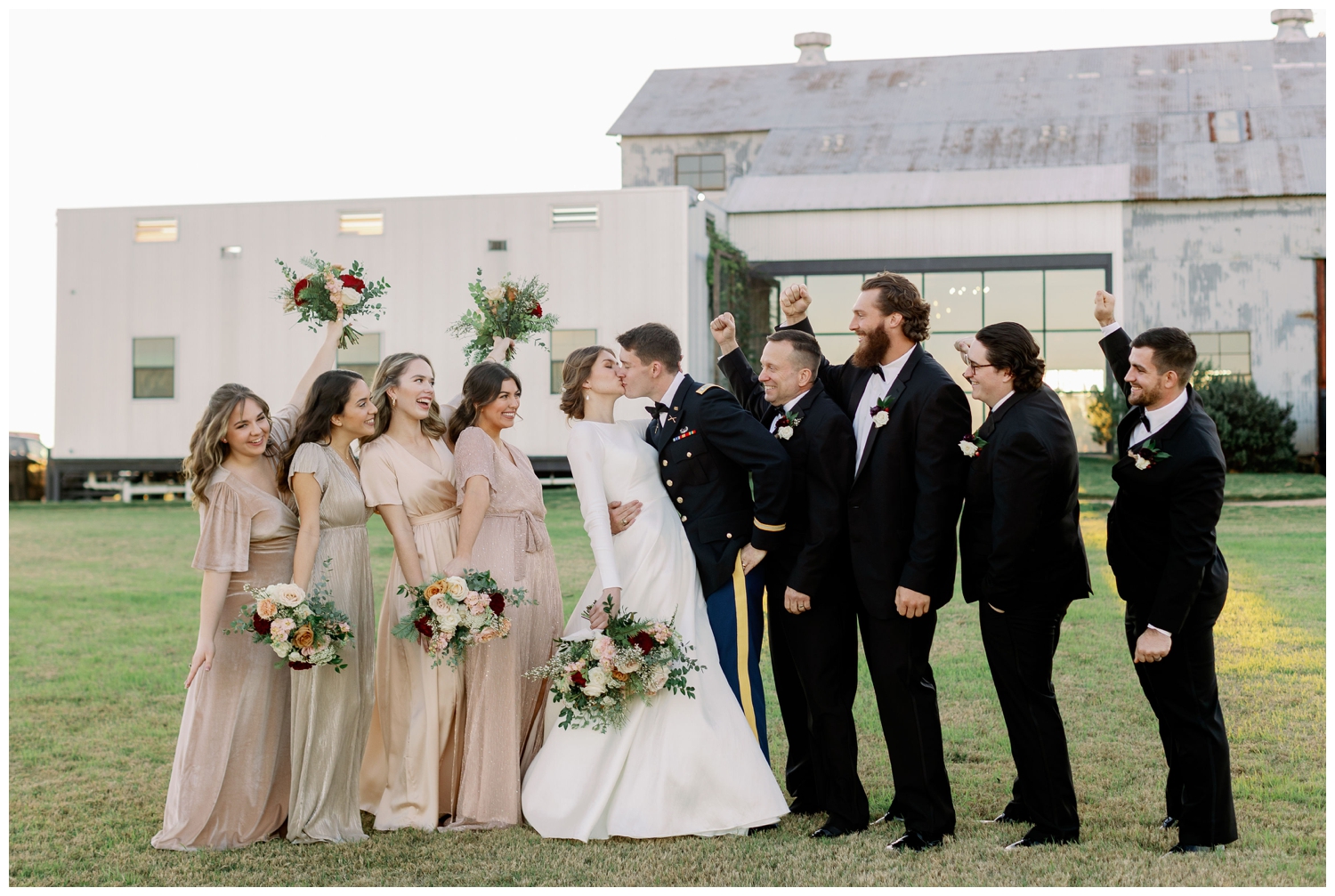 bride and groom kissing outdoors with bridal party cheering College Station wedding photography