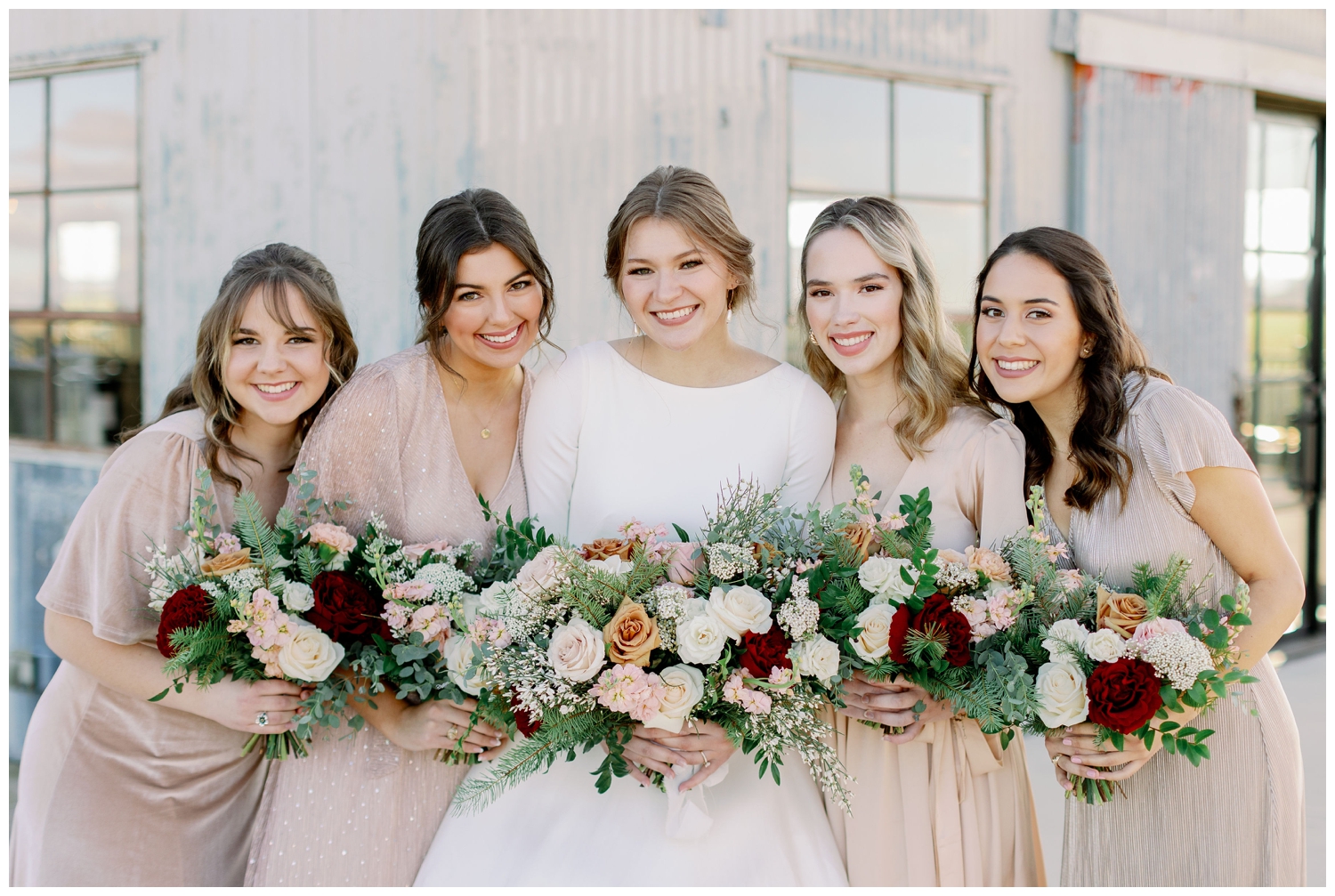 bride smiling with bridesmaids in blush dresses holding bouquets for College Station wedding photography
