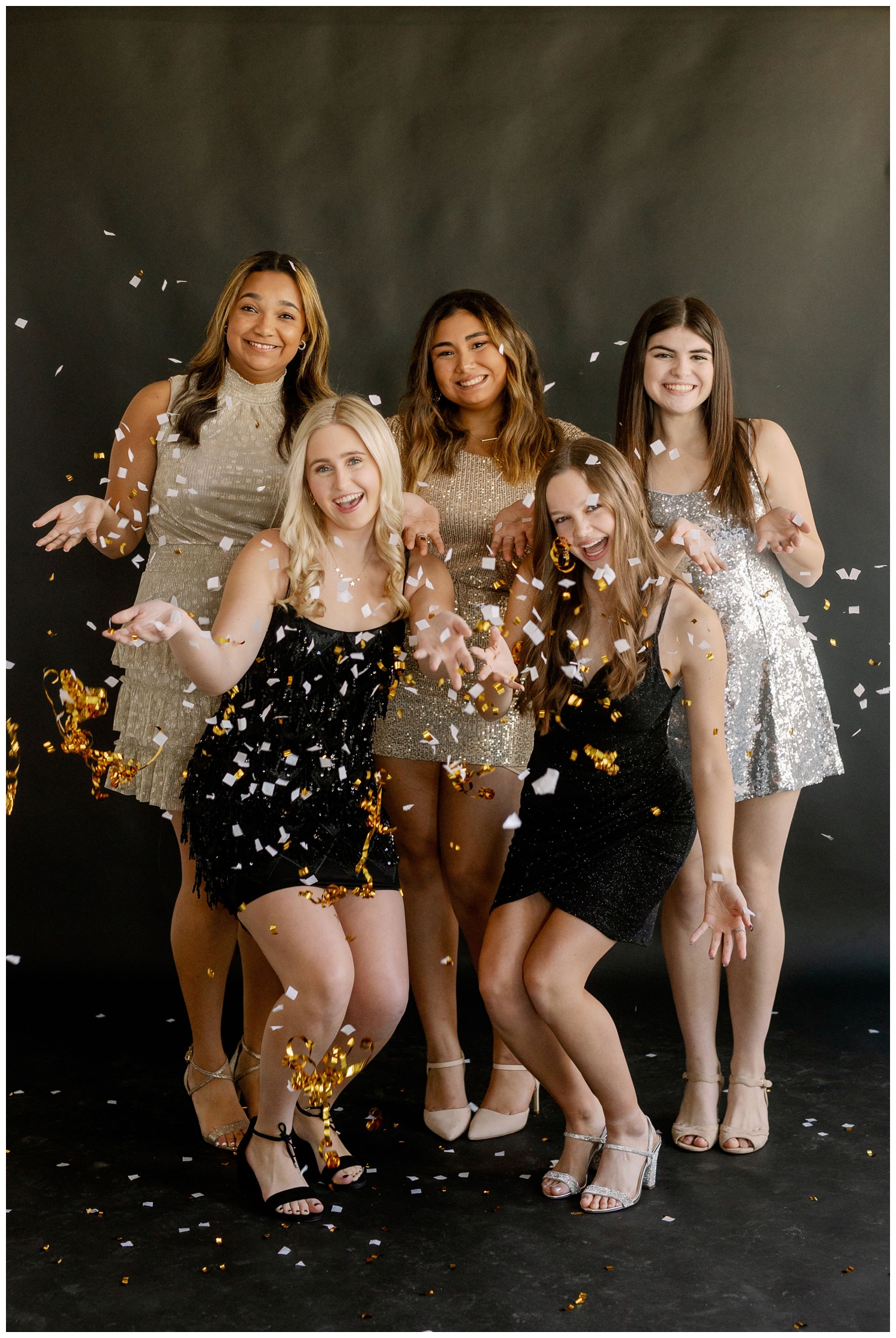 group of high school senior girls throwing confetti while in sparkly dresses