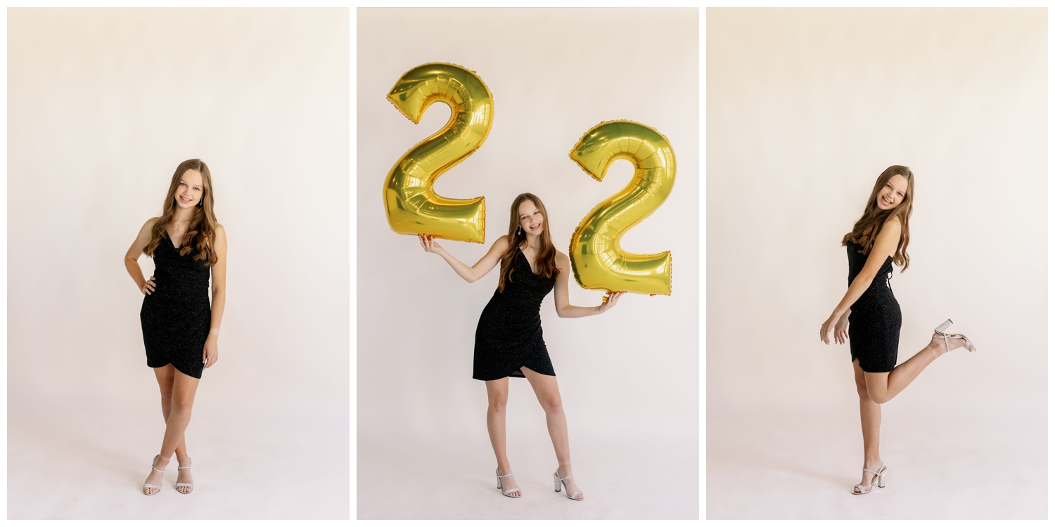 senior girl in black dress laughing and holding balloons on white background fro New Years senior pictures