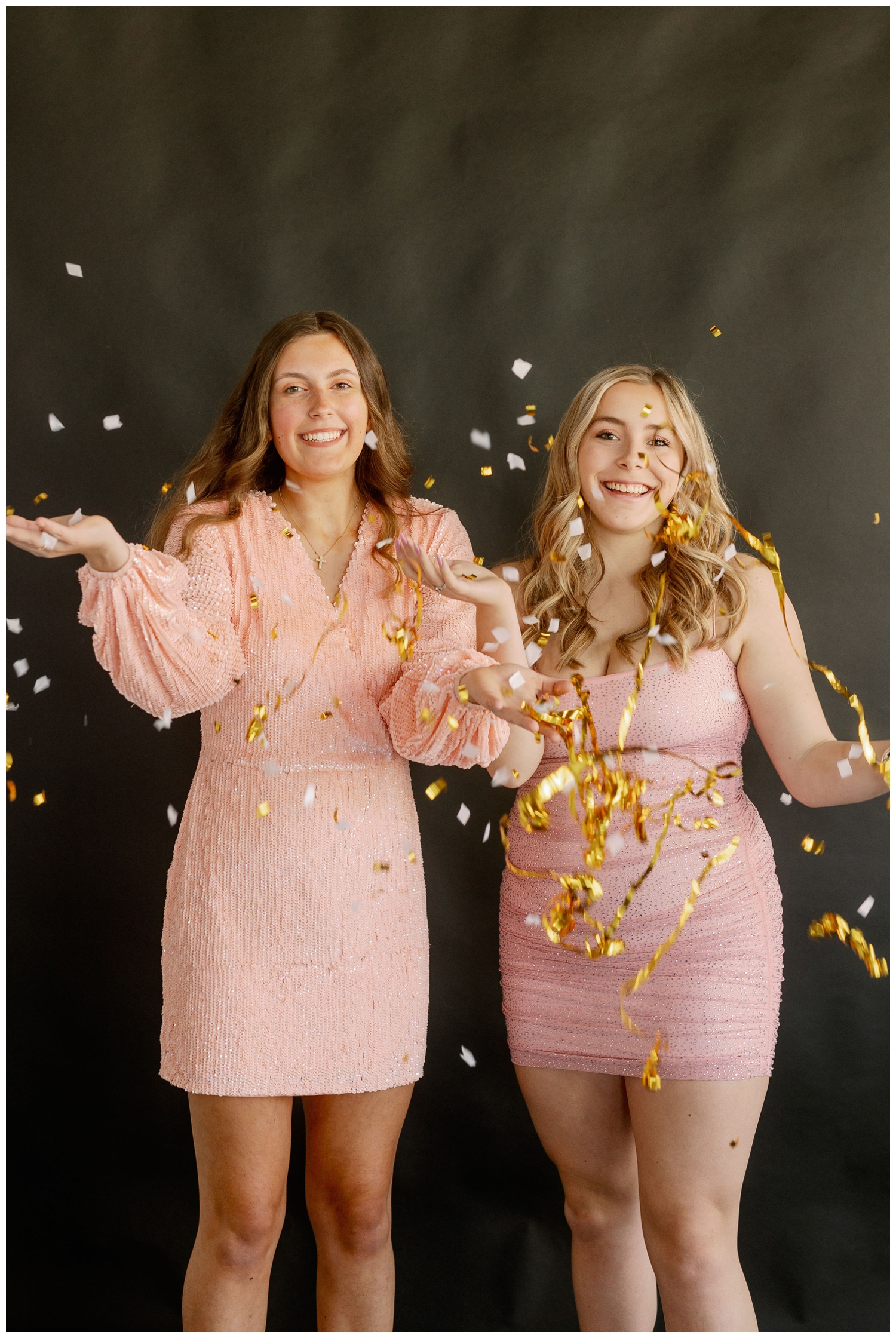 two high school senior girls throwing up confetti for New Years senior pictures