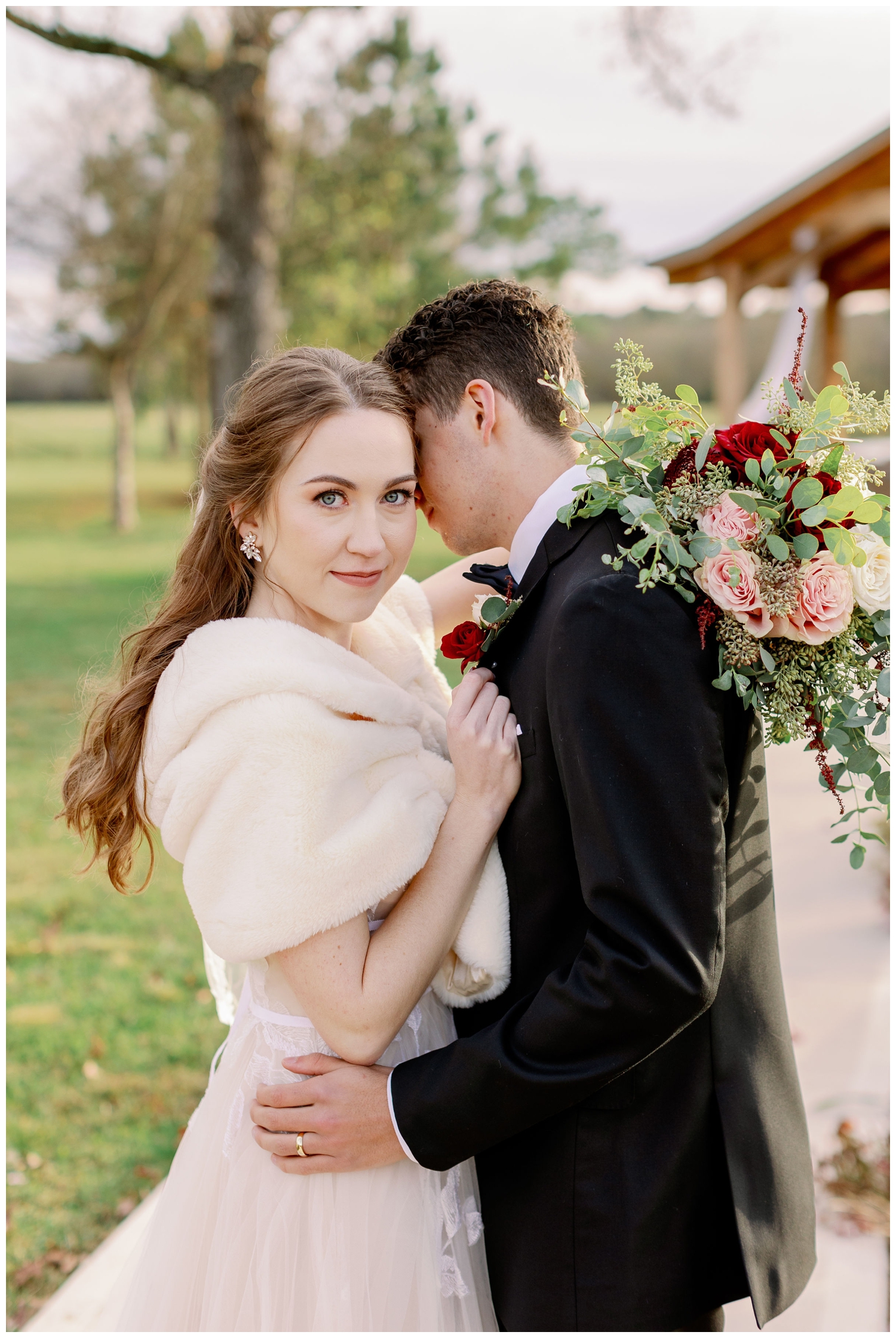 bride looking at camera with groom nuzzling in outside Union Ranch