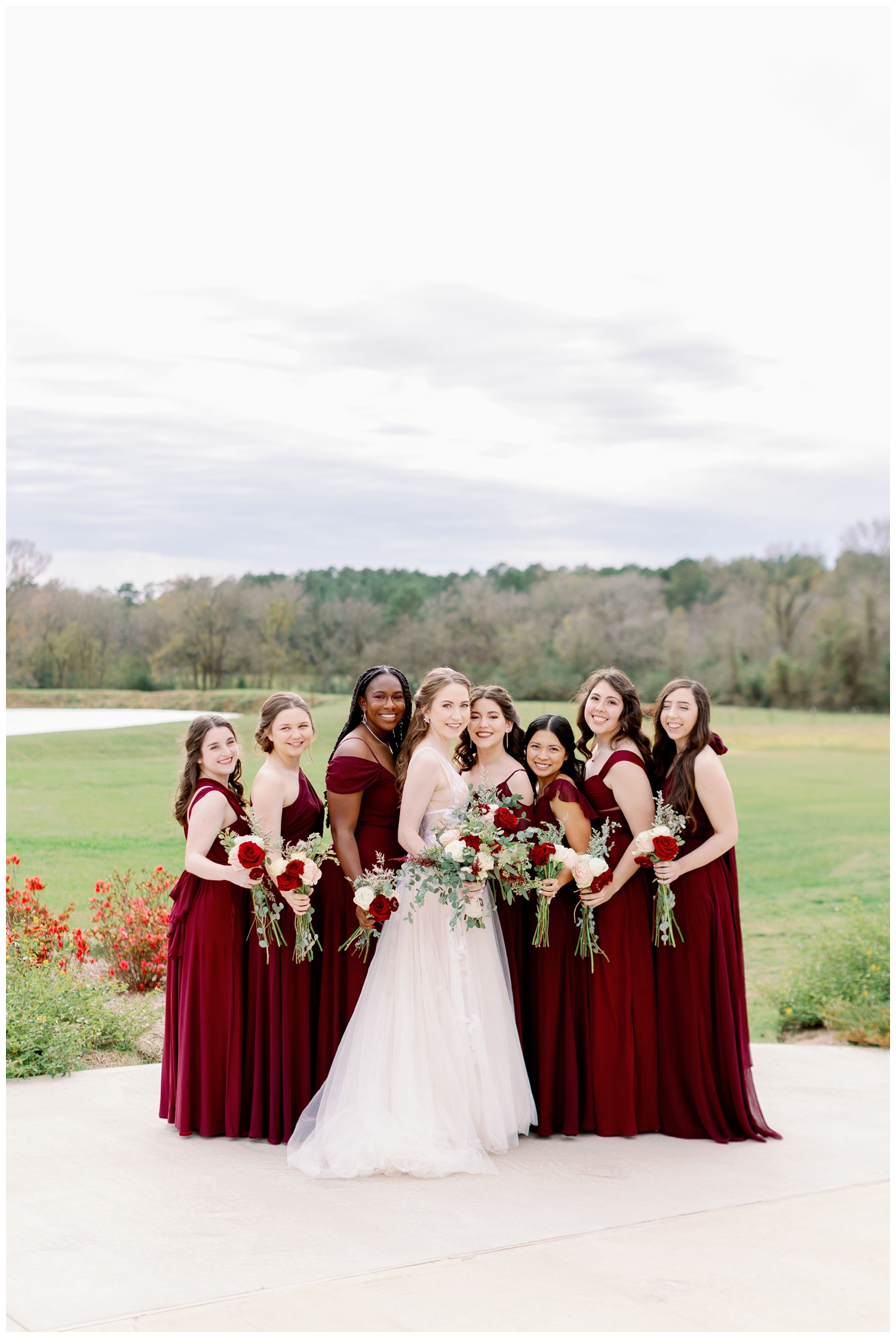 bride with bridesmaids in burgundy dresses posing and smiling for winter Union Ranch Wedding