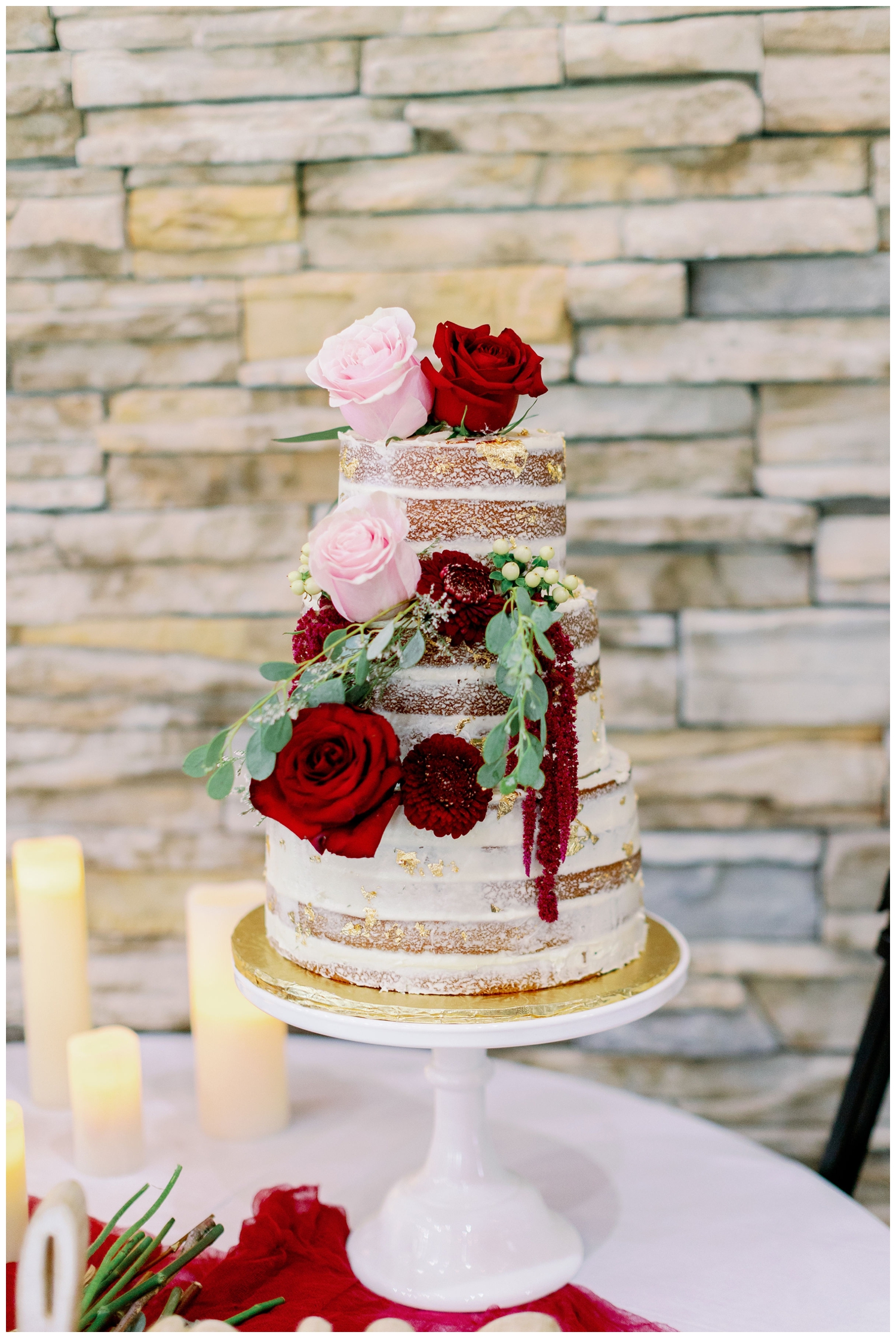 three tiered white cake with pink and red roses