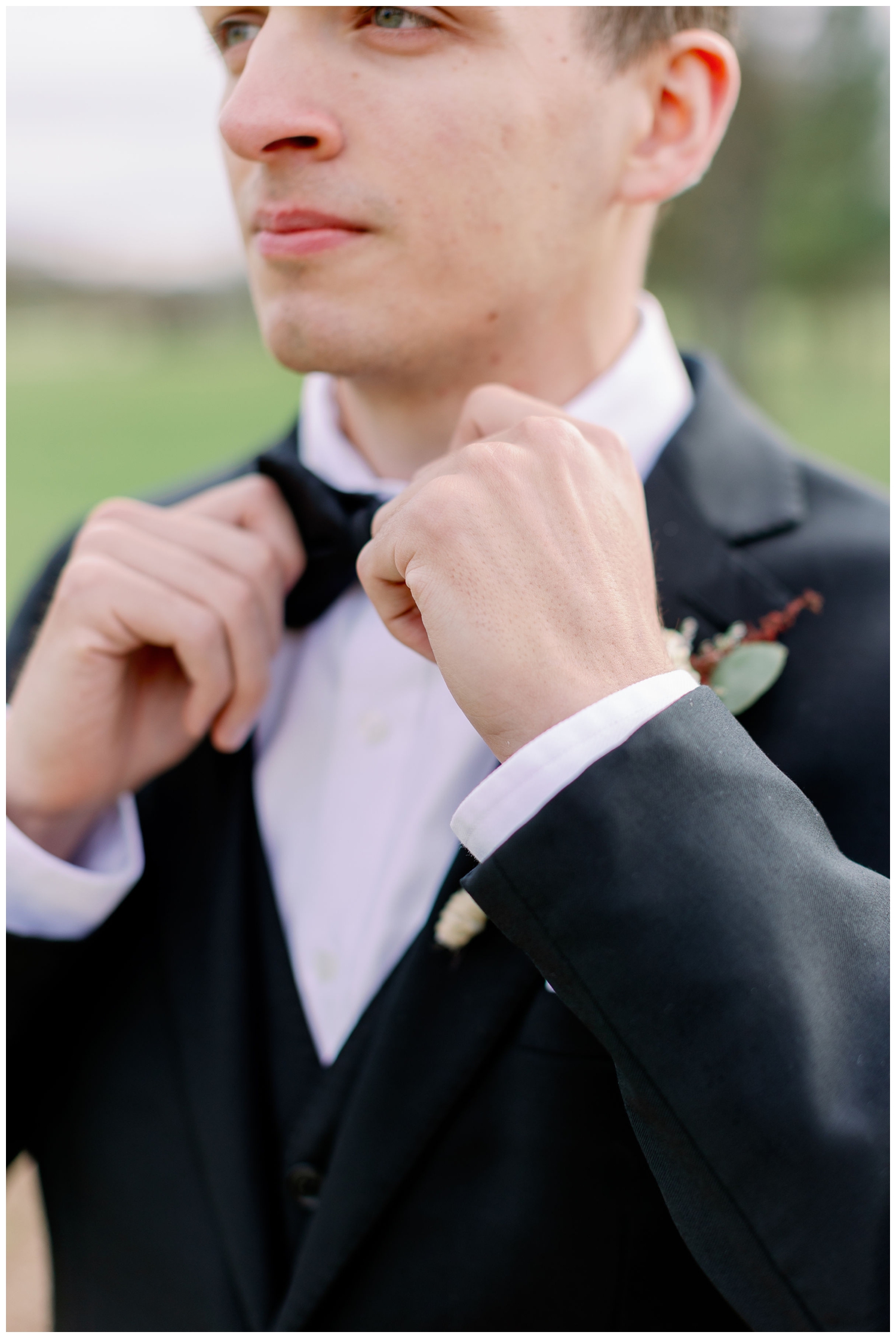 groom fastening black bow tie outside Union Ranch Wedding venue