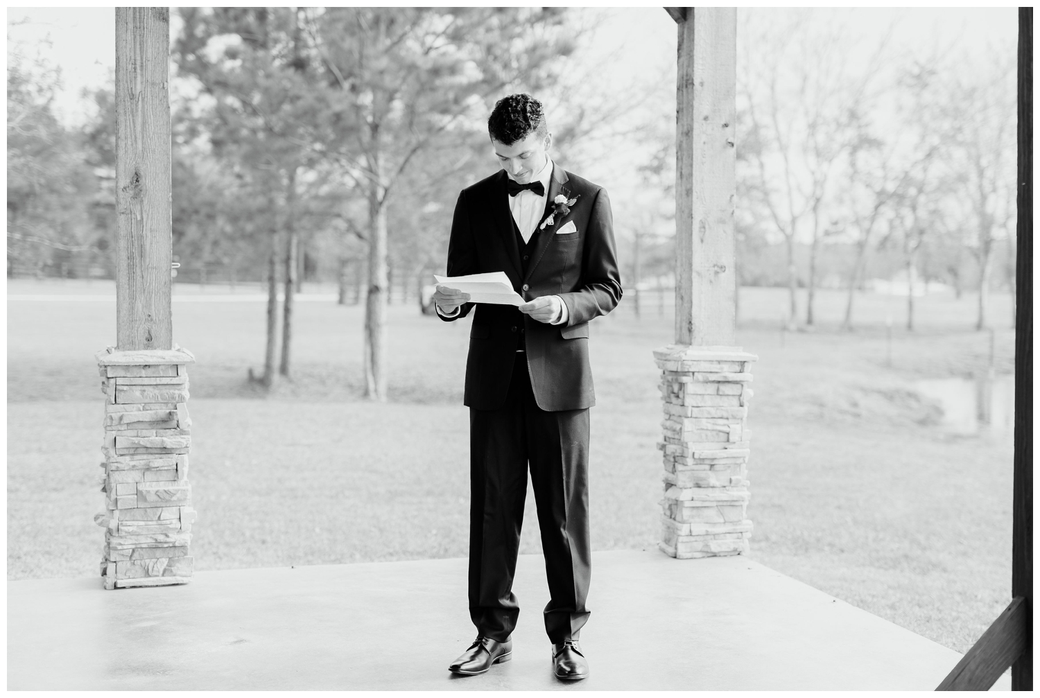 black and white image of groom in black tux reading love letter at winter Union Ranch Wedding