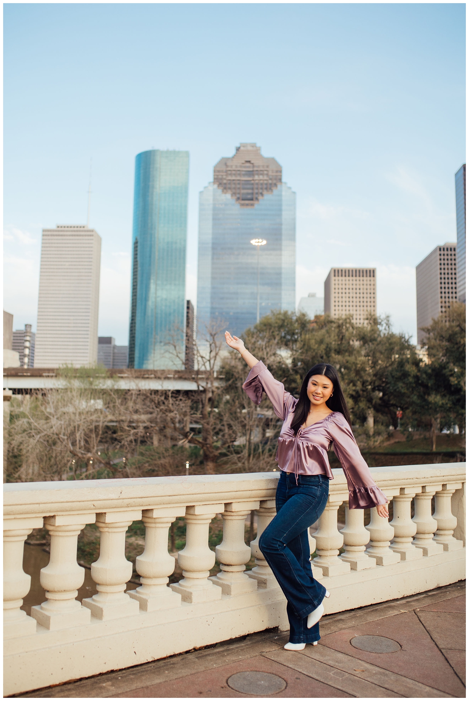 girl in jeans and plumb blouse standing in front of Houston skyline