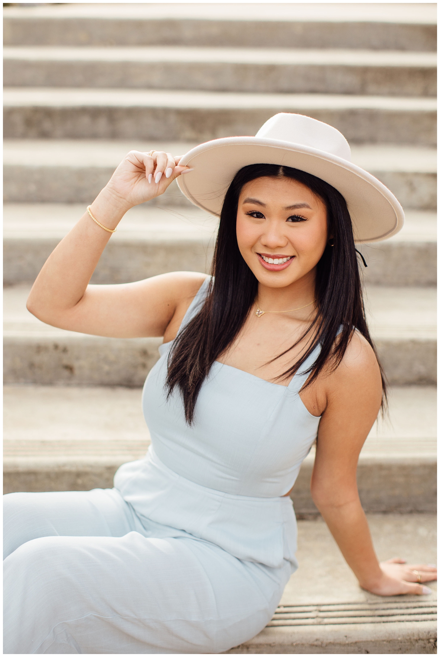 high school senior girl sitting on stairs wearing white hat
