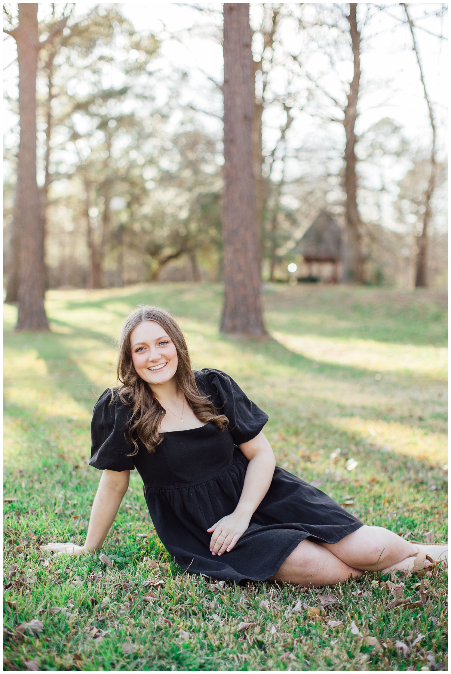 high school senior girl in black dress sitting on grass