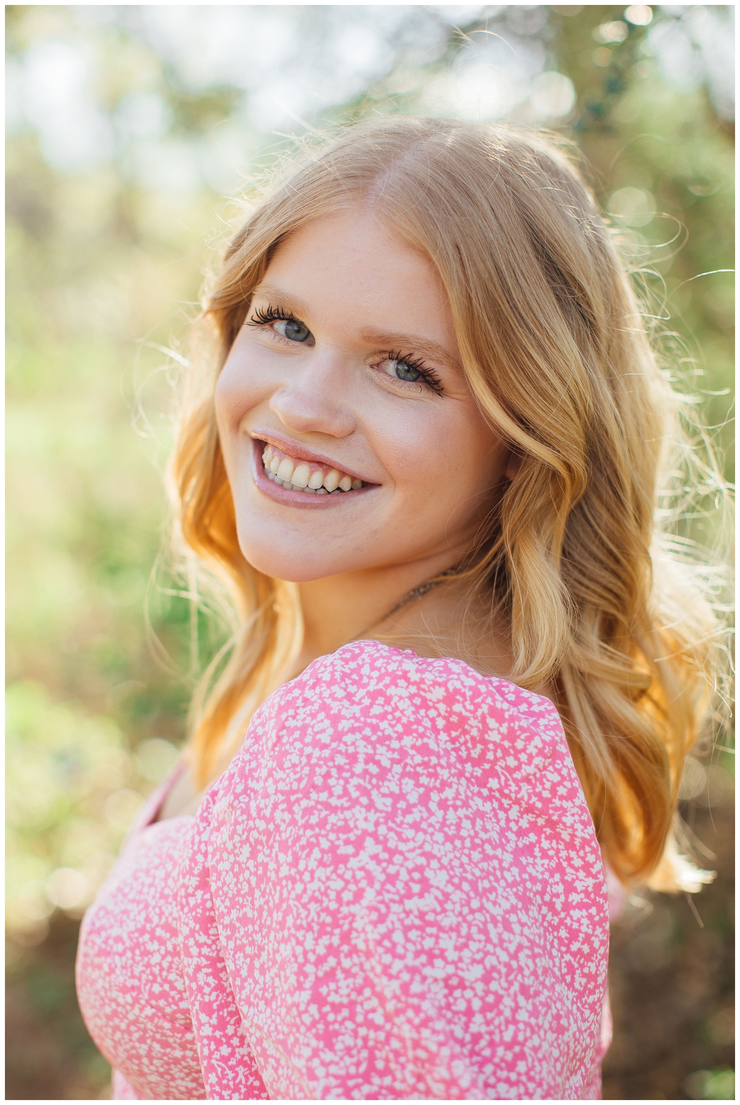 closeup up of high school senior girl smiling at camera in pink shirt Houston Arboretum Houston Senior Portrait Photographer