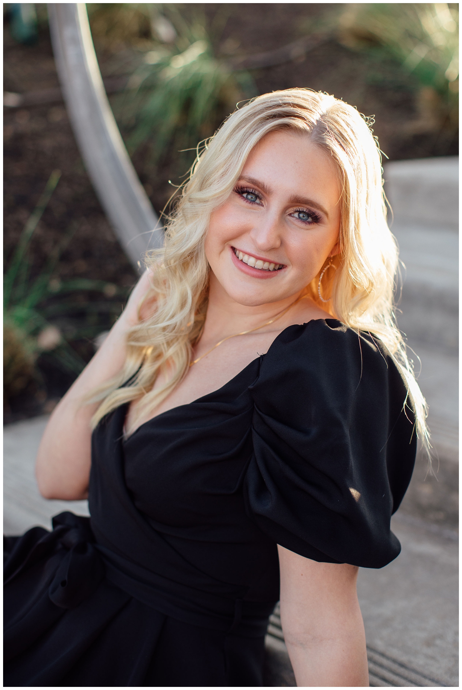 girl wearing black dress with hand in hair sitting on stairs senior pictures Houston Texas Sabine Street