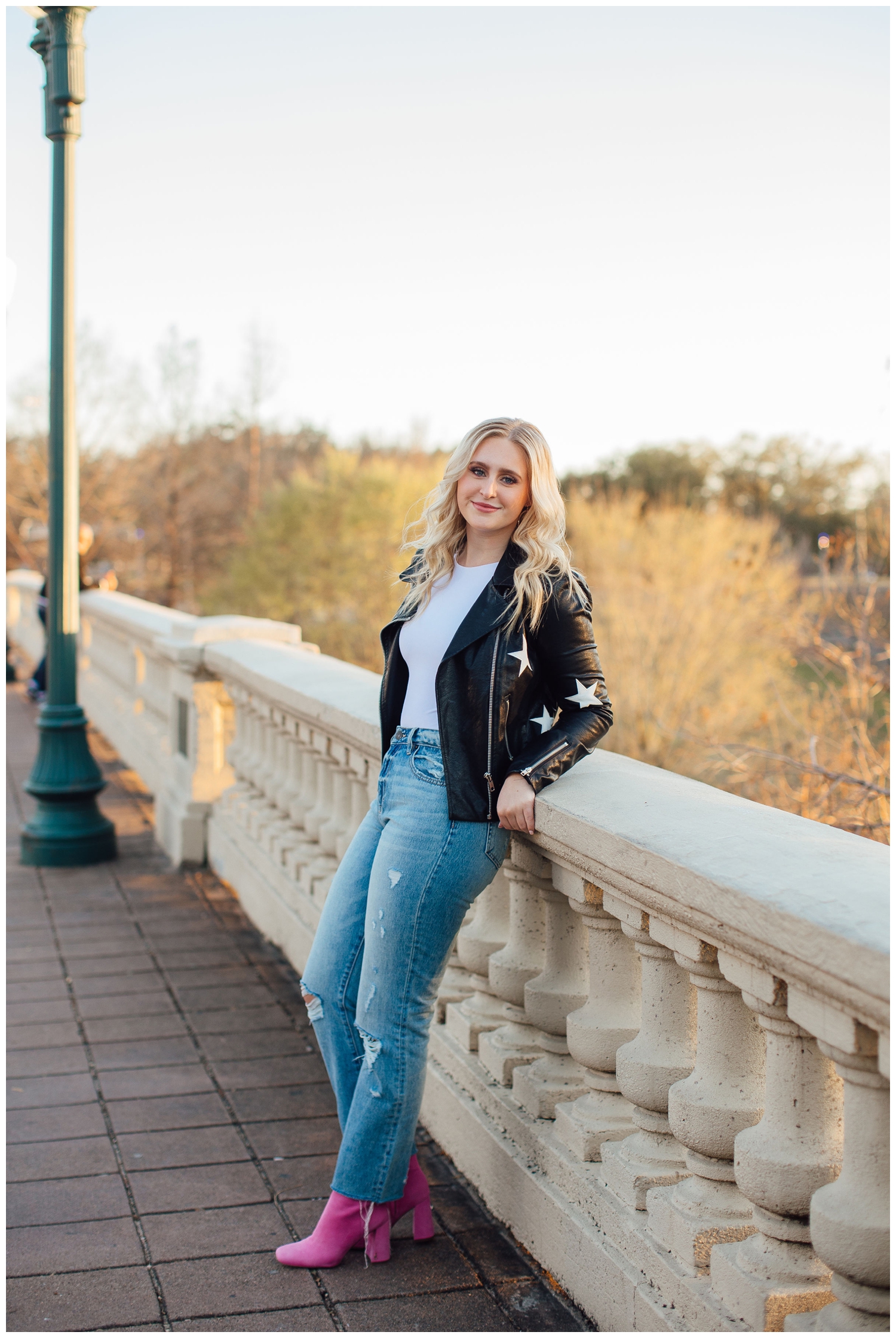 high school senior standing on Sabine Street bridge in jeans and black jacket with stars