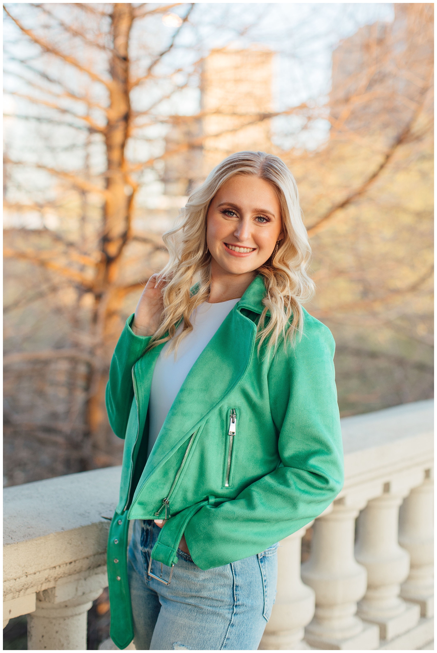 Houston high school senior wearing bright green jacket posing with hand in hair on Sabine Street Bridge