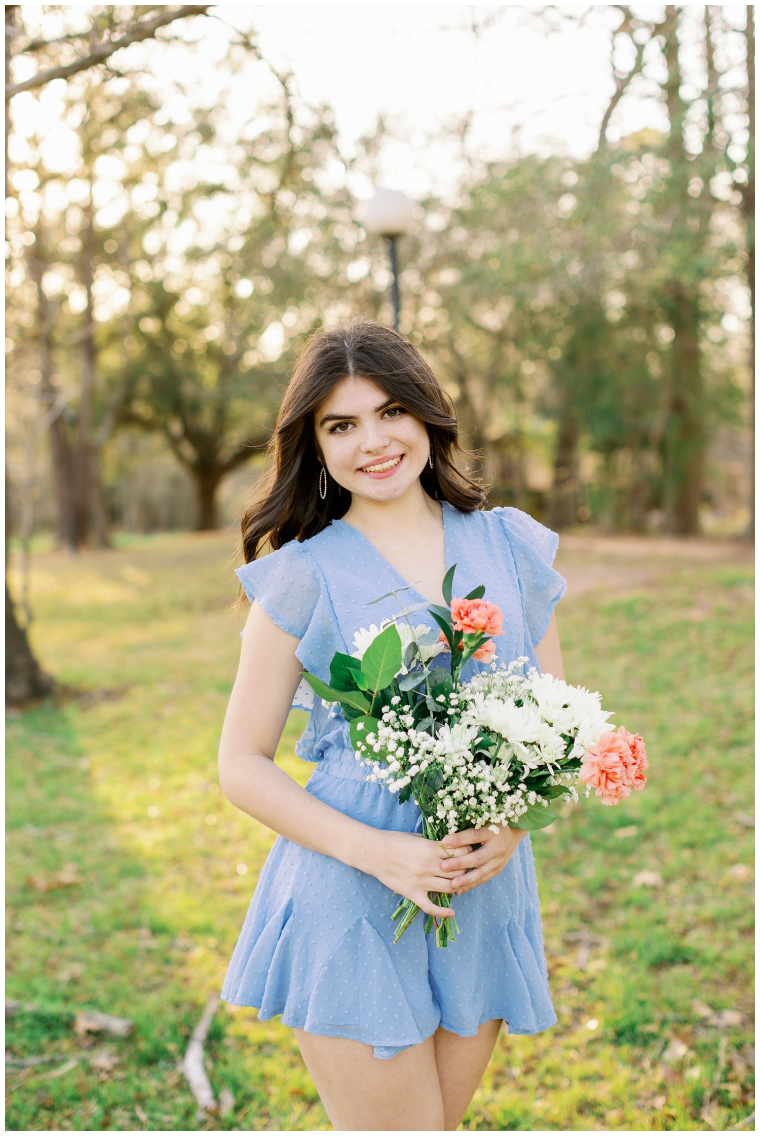 spring picnic senior pictures of girl in blue dress holding flower outside