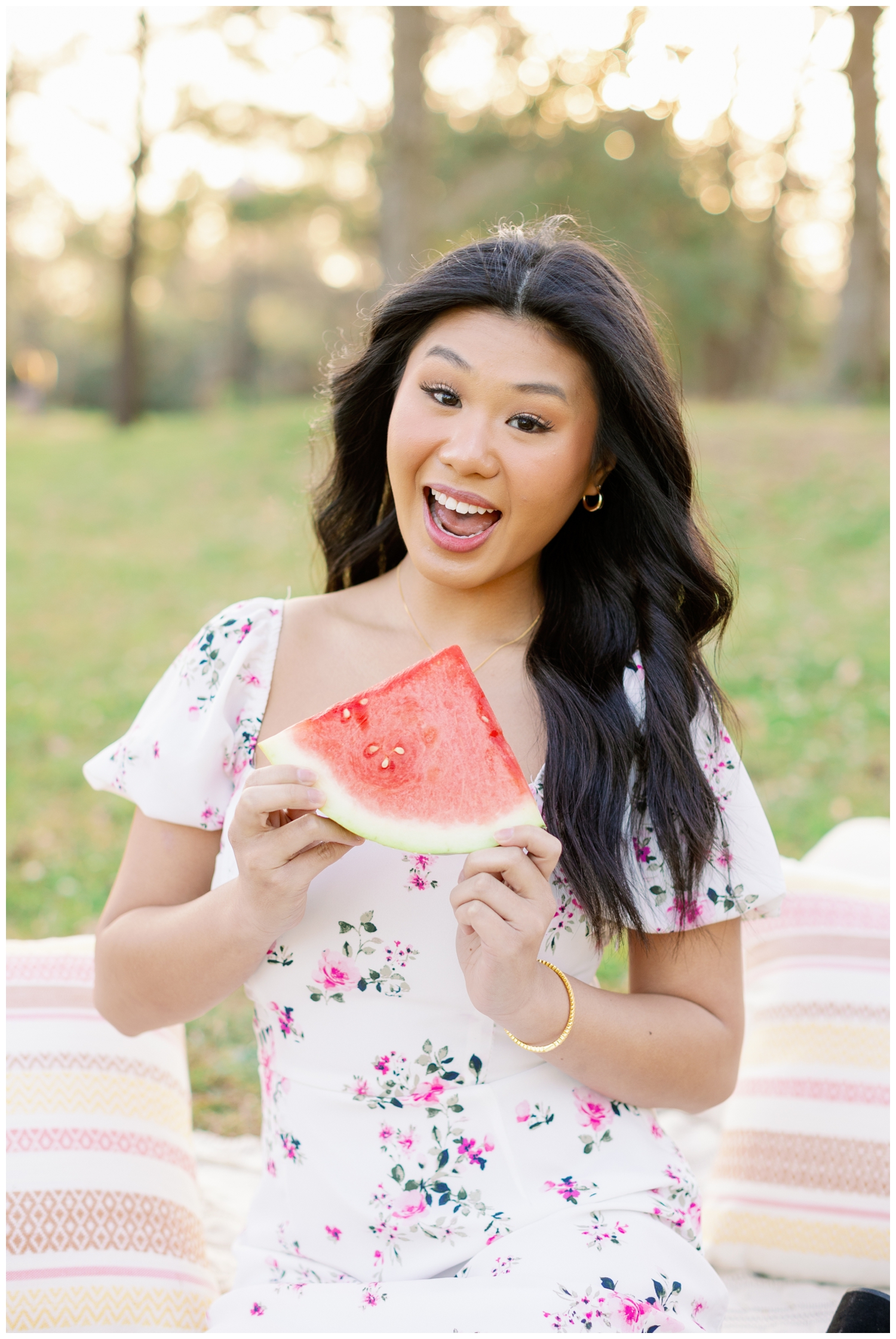 high school Houston girl holding slice of watermelon and smiling for spring picnic senior pictures