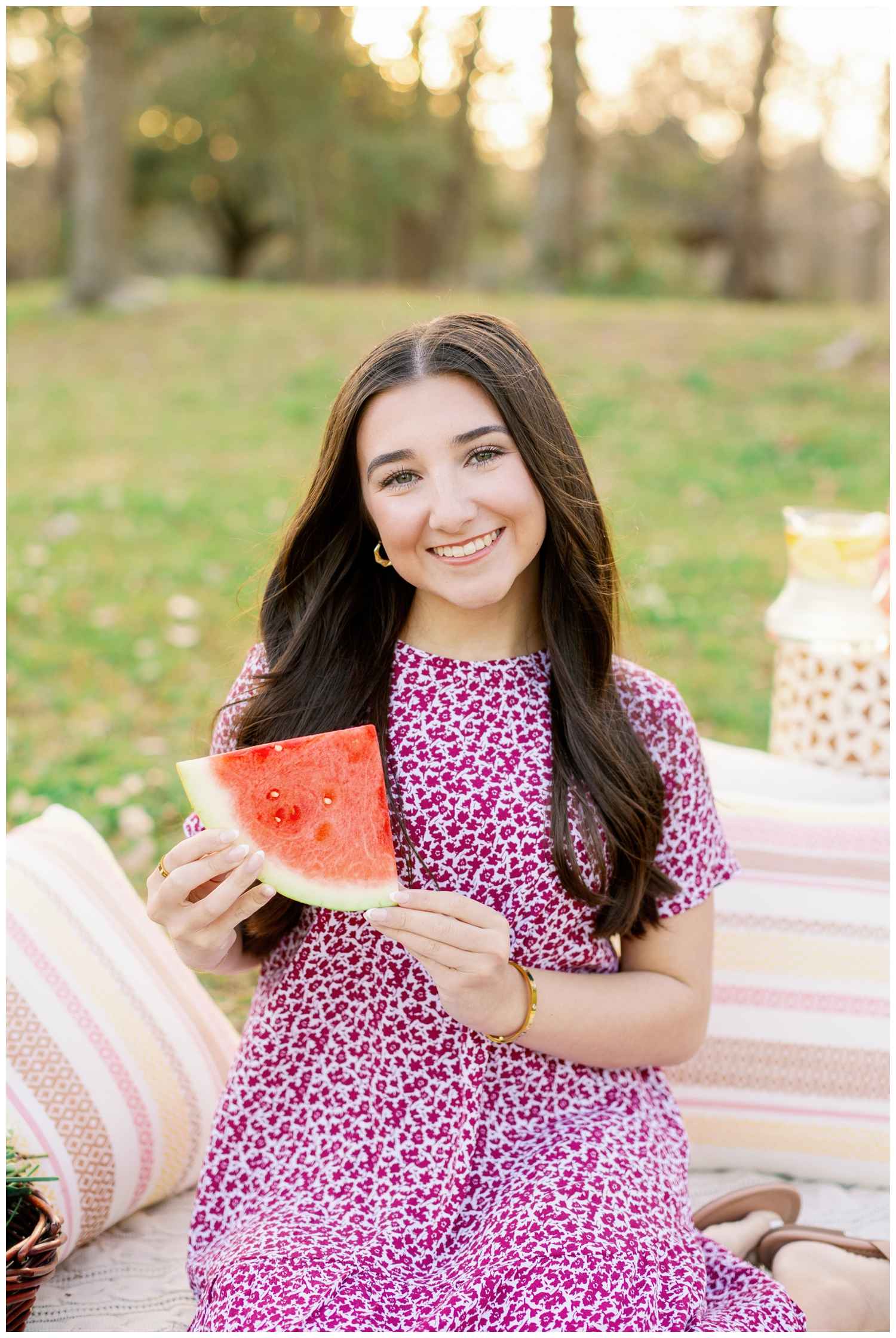 high school senior girl sitting on blanket holding watermelon slice