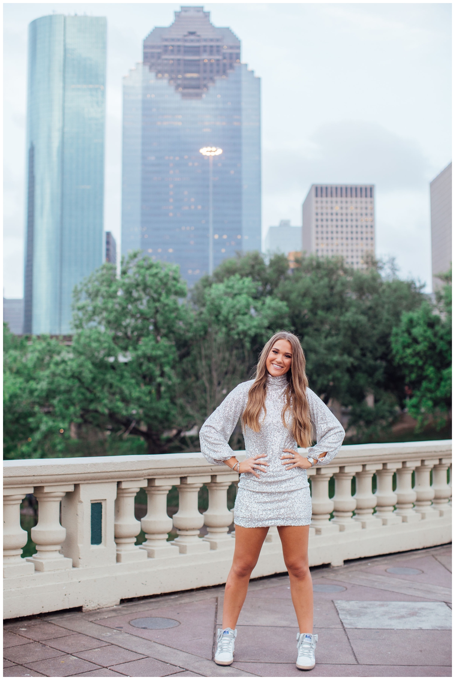 high school senior girl standing with hands on hip in front of Houston skyline for vibrant senior pictures in Houston