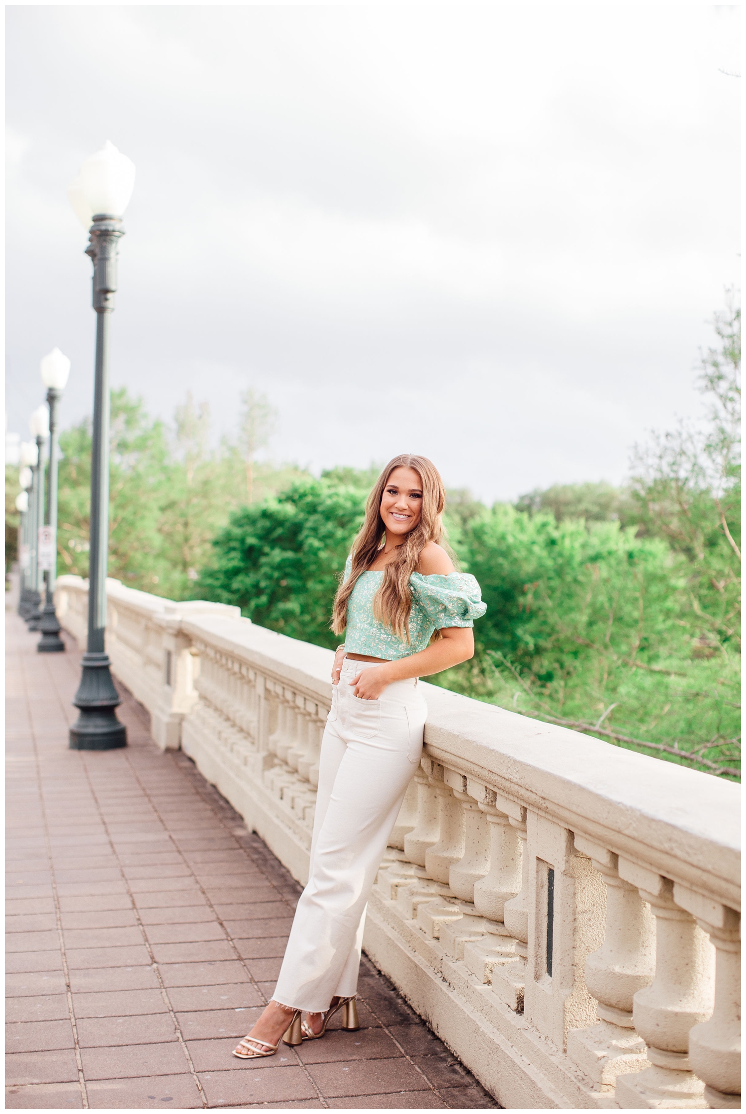 girl in white pants and green blouse leaning on Sabine Street Bridge