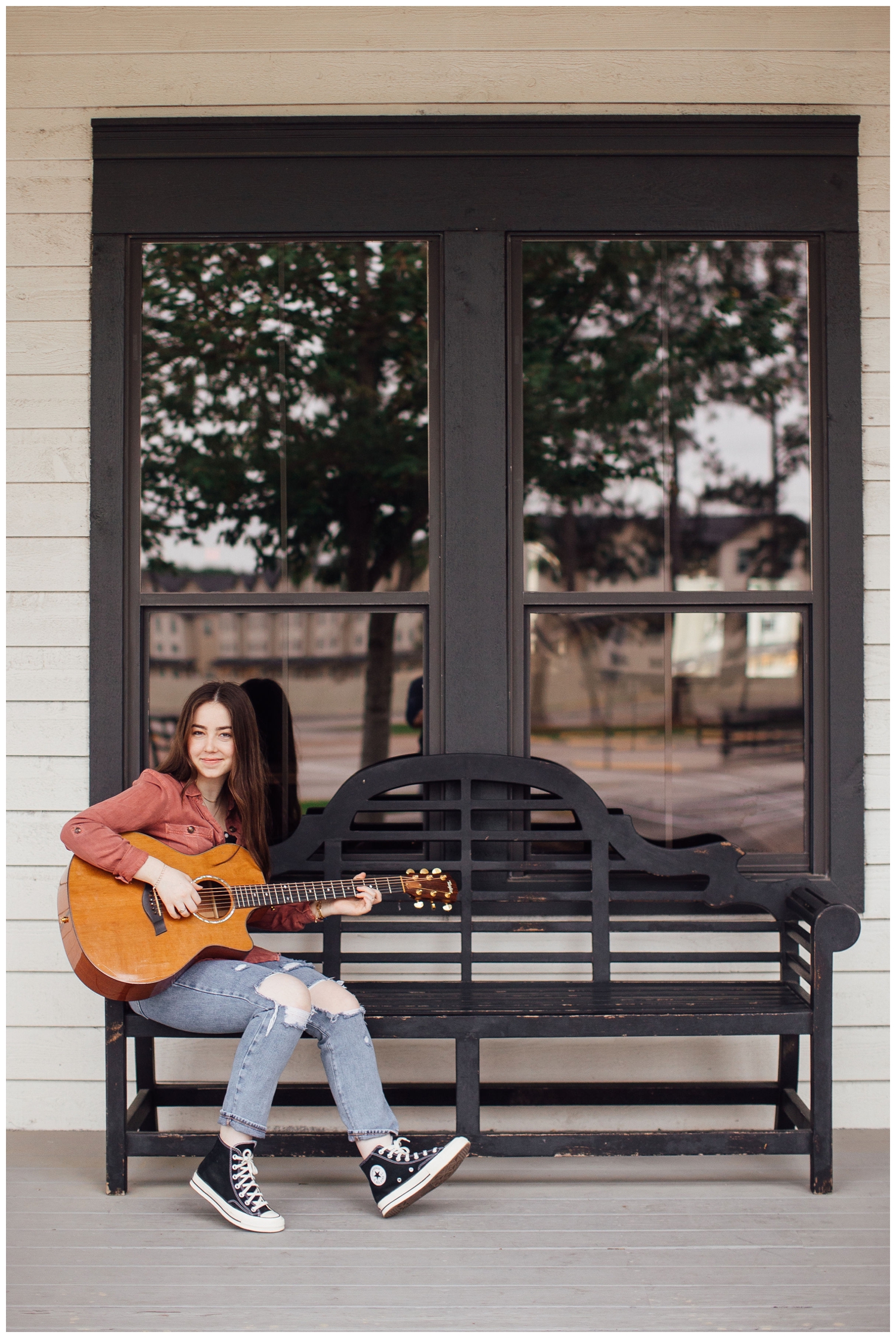 girl sitting on black bench playing guitar at Cy-Hope Houston senior photos with guitar