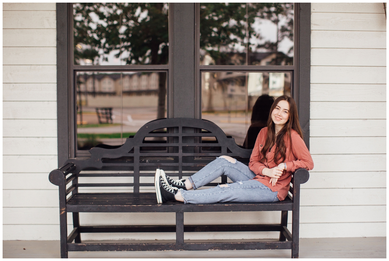 girl in jeans sitting on bench for Houston senior photos with guitar