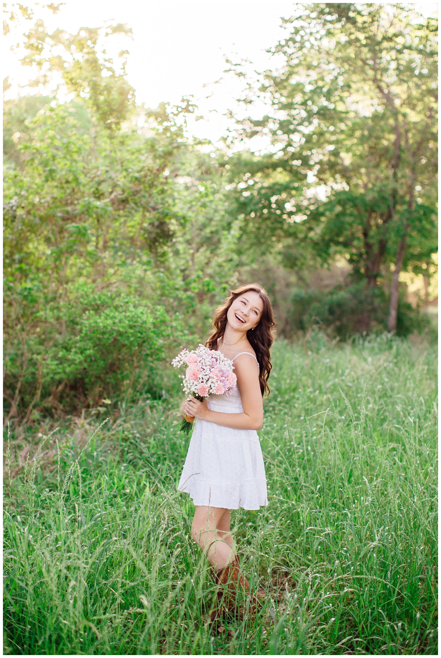 girl in white sundress standing in field holding bouquet spring senior photos Houston