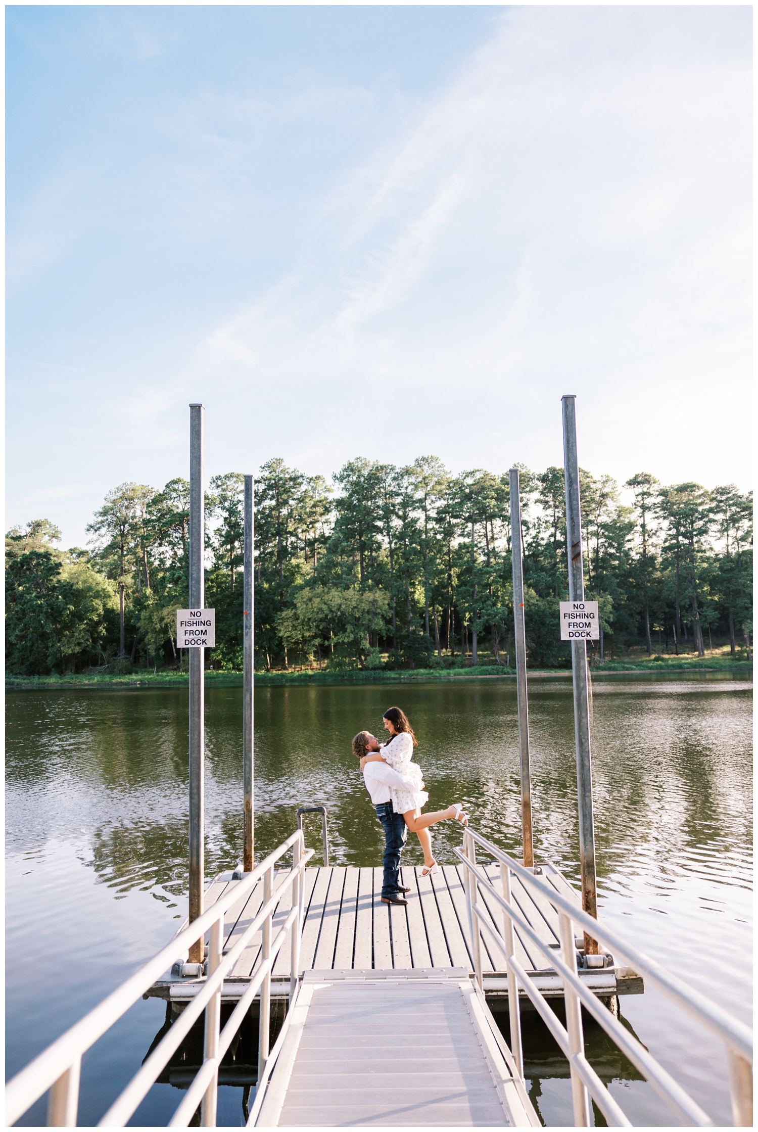 couple doing a lift on the boat dock in front of lake during Engagement Photos Huntsville Texas