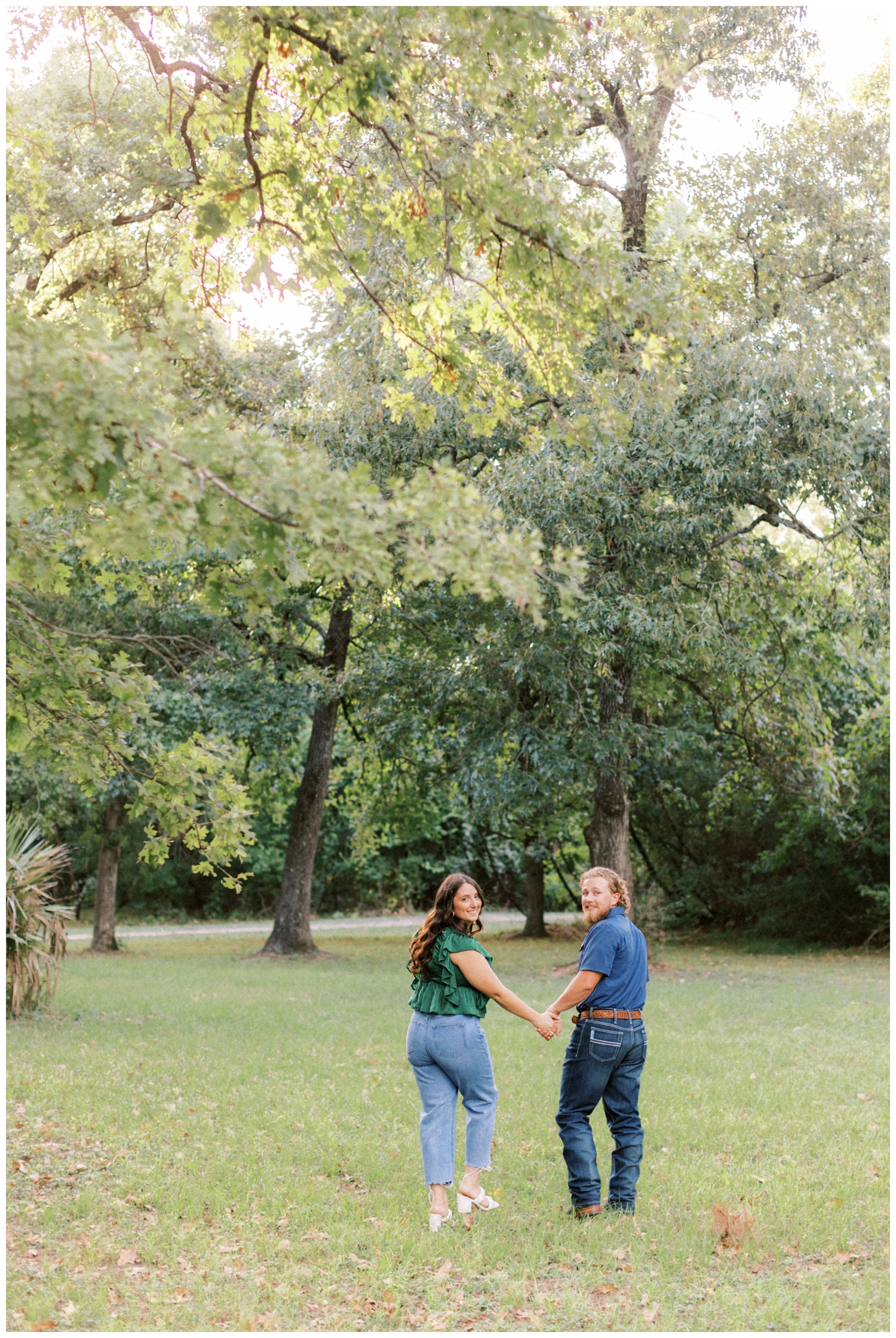 couple holding hands and walking under trees at Huntsville State Park