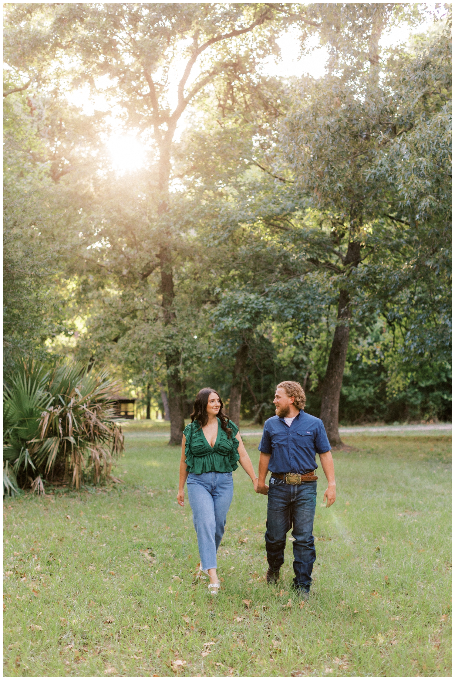 couple in jeans and green shirt holding hands walking with sunsetting at engagement photos Huntsville, Texas
