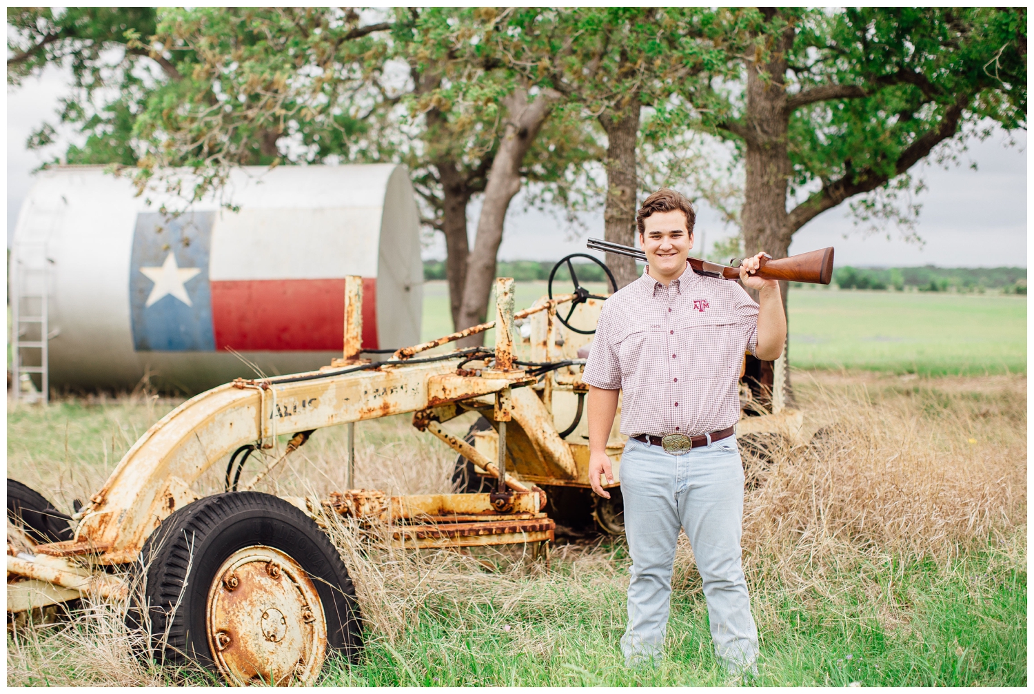 outdoor senior guy pictures with guy standing in front of tractor in jeans, plaid shirt and holding a gun