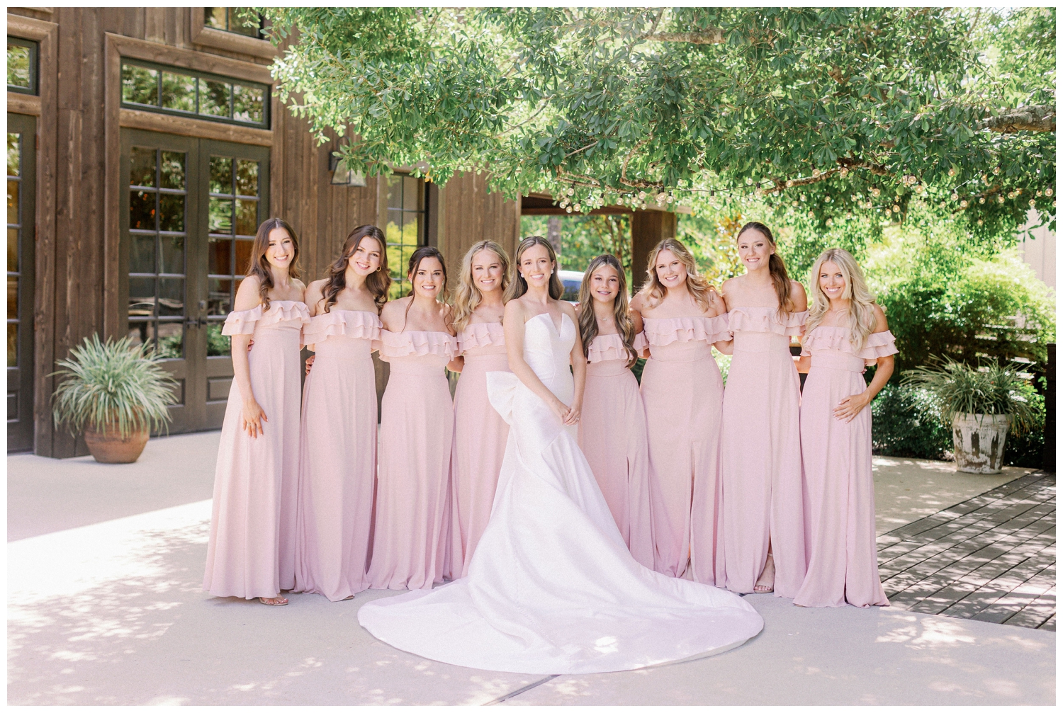 bride standing outside The Carriage House Houston with bridesmaids in blush dresses