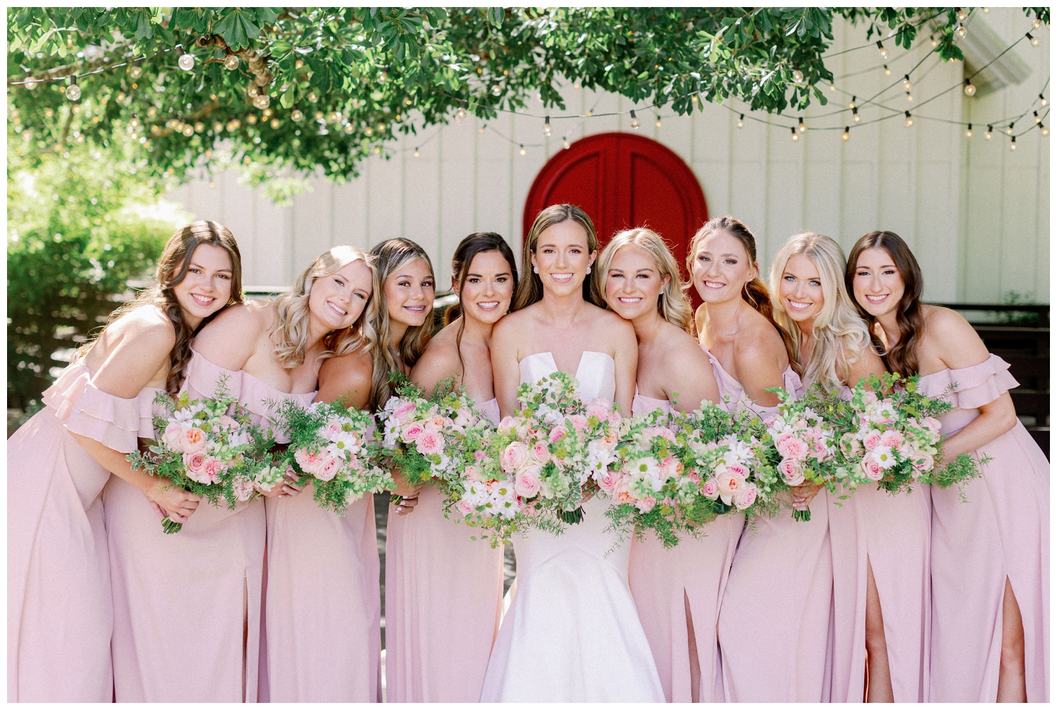bride outside The Carriage House Houston surrounding by bridesmaids with bouquets and blush dresses