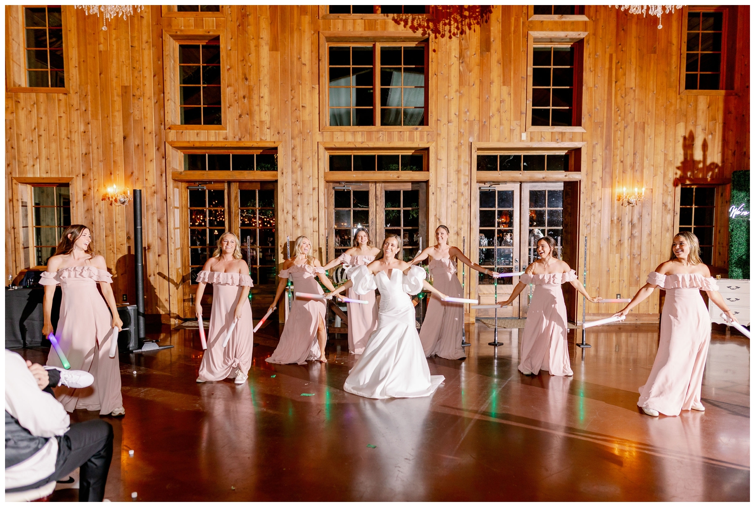 bride and bridesmaids in blush dresses dancing as a group at reception
