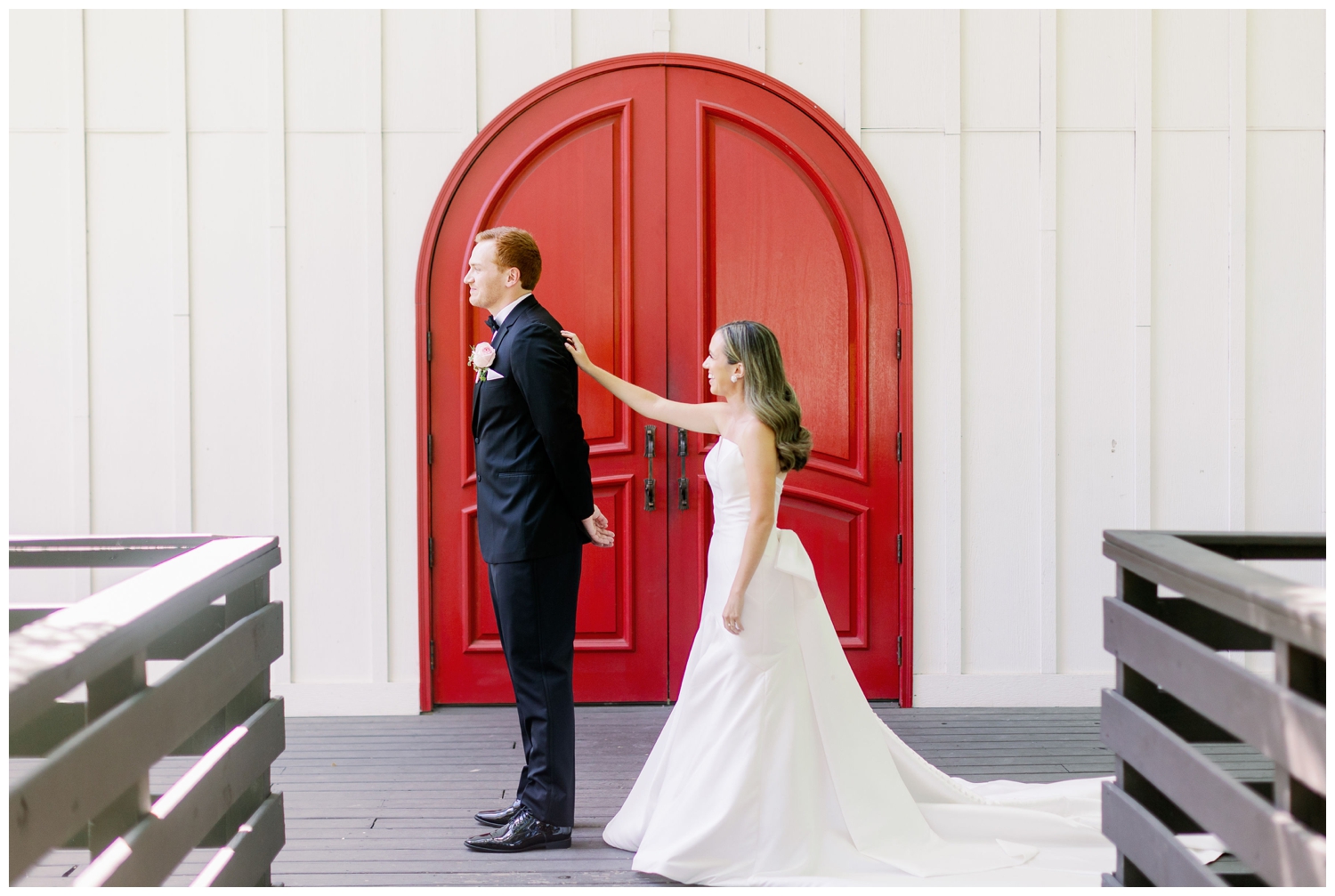 bride touching grooms shoulder for first look in front of red door at The Carriage House Houston