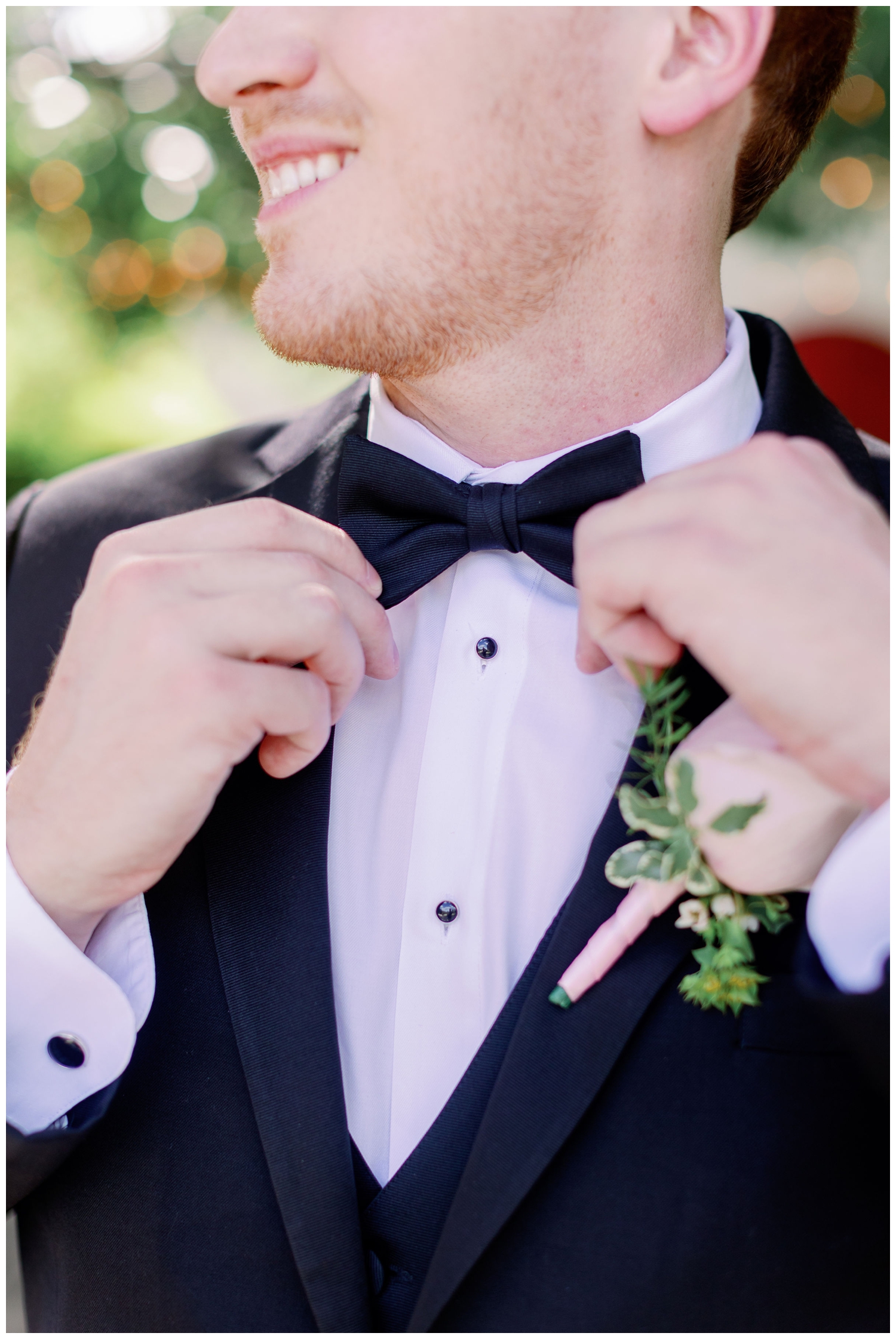 close up portrait of groom straightening bowtie
