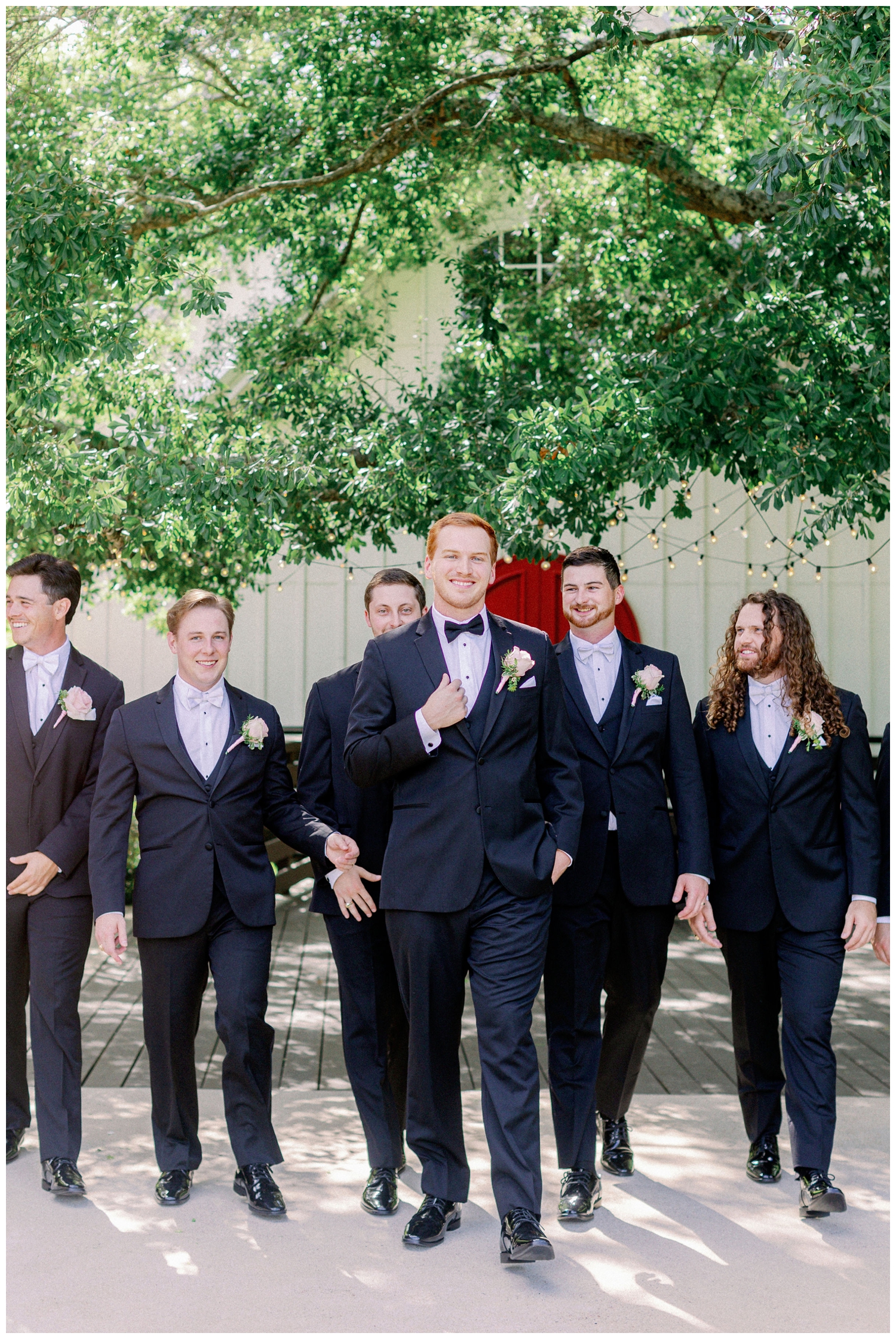 groom walking with groomsmen in black tuxes outdoors at The Carriage House Houston
