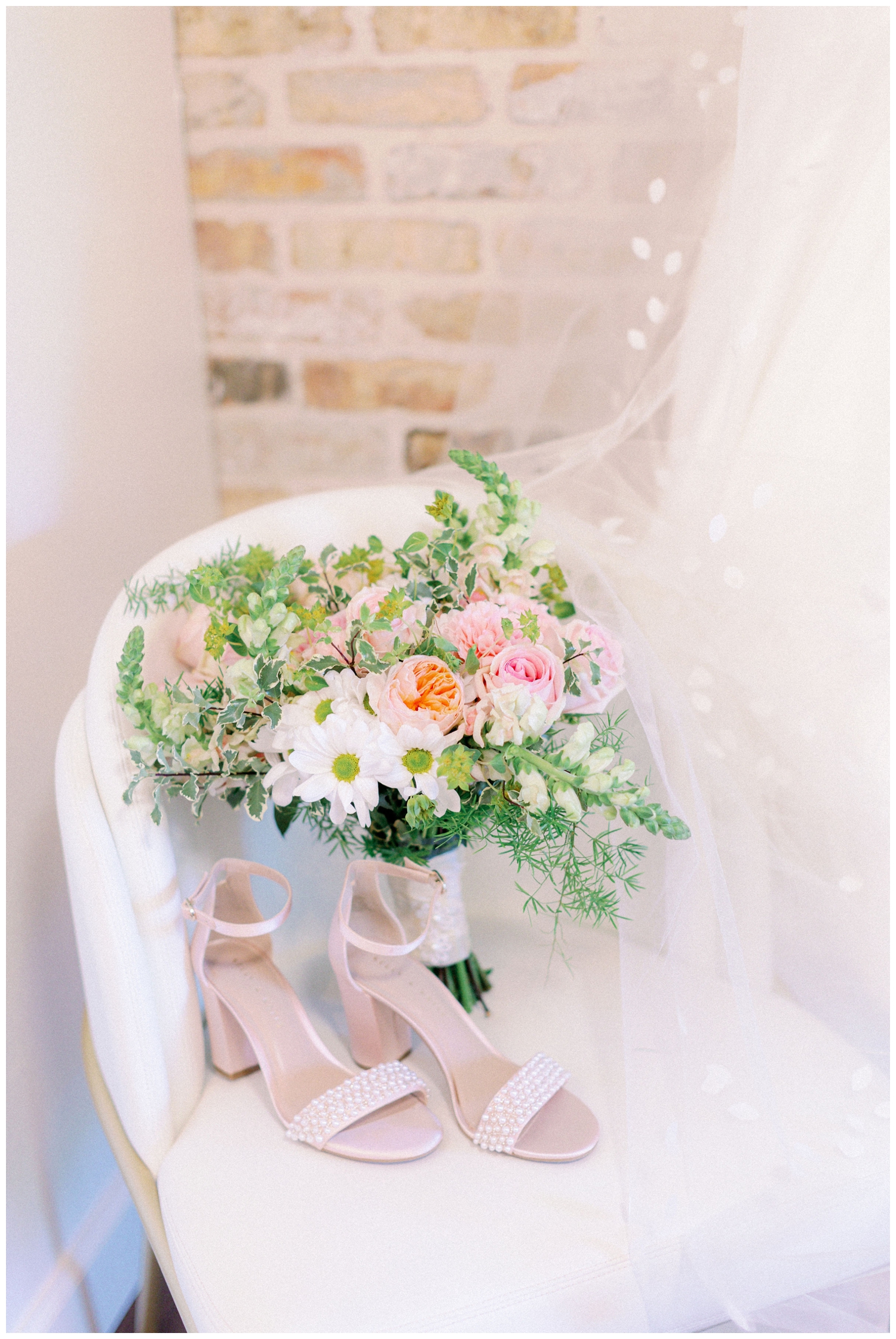 white pink bouquet and heels on chair with wedding gown hanging