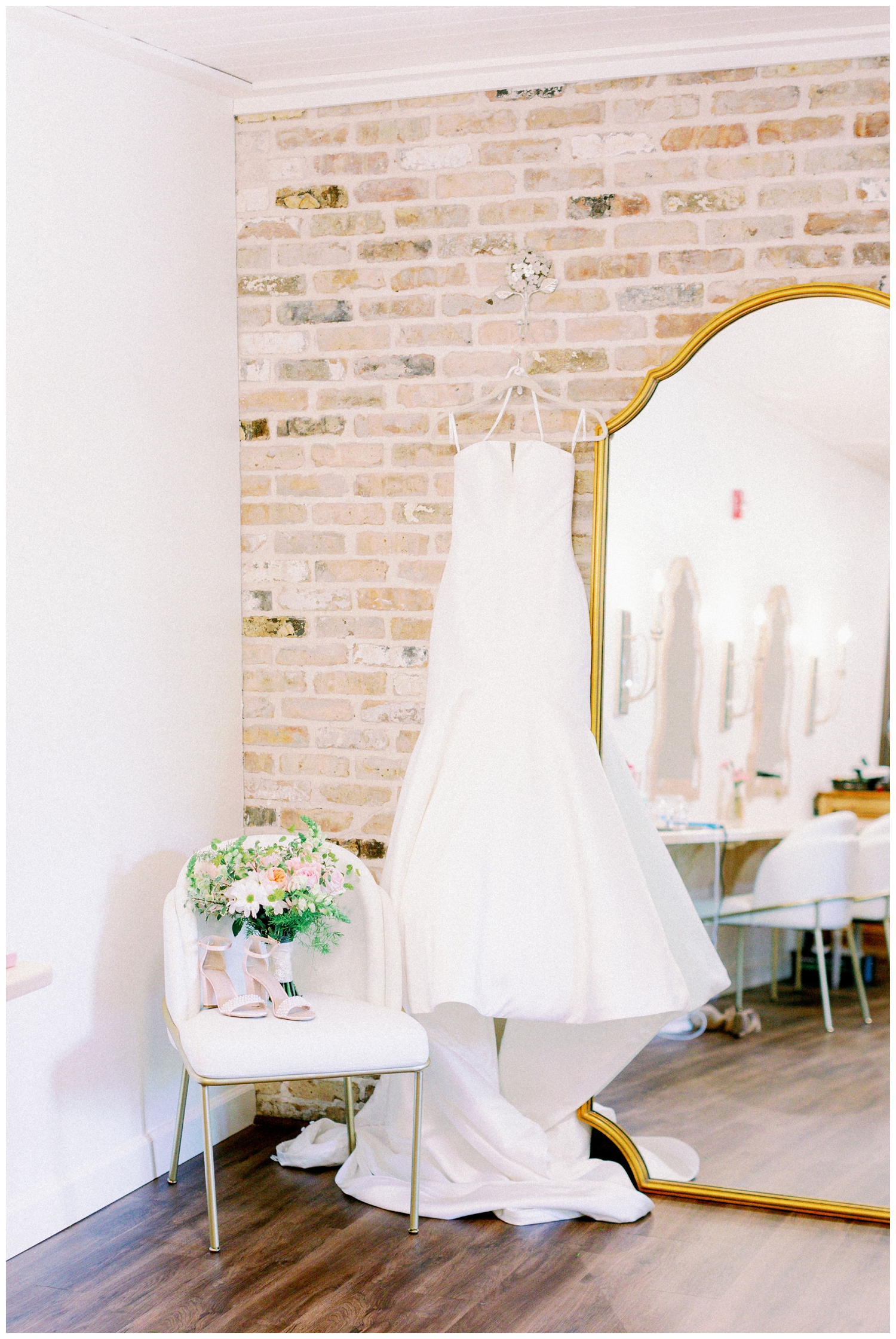 wedding gown hanging inside The Carriage House Houston with shoes and bouquet in a chair