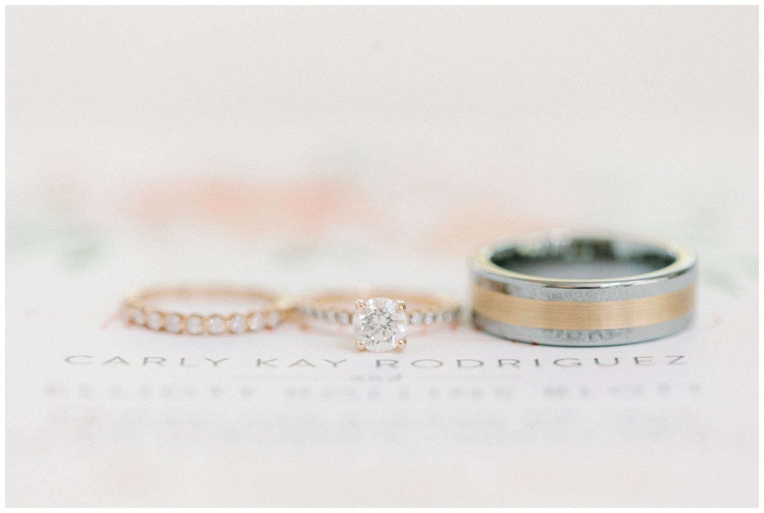 wedding rings on top of white invitation suite flatlay