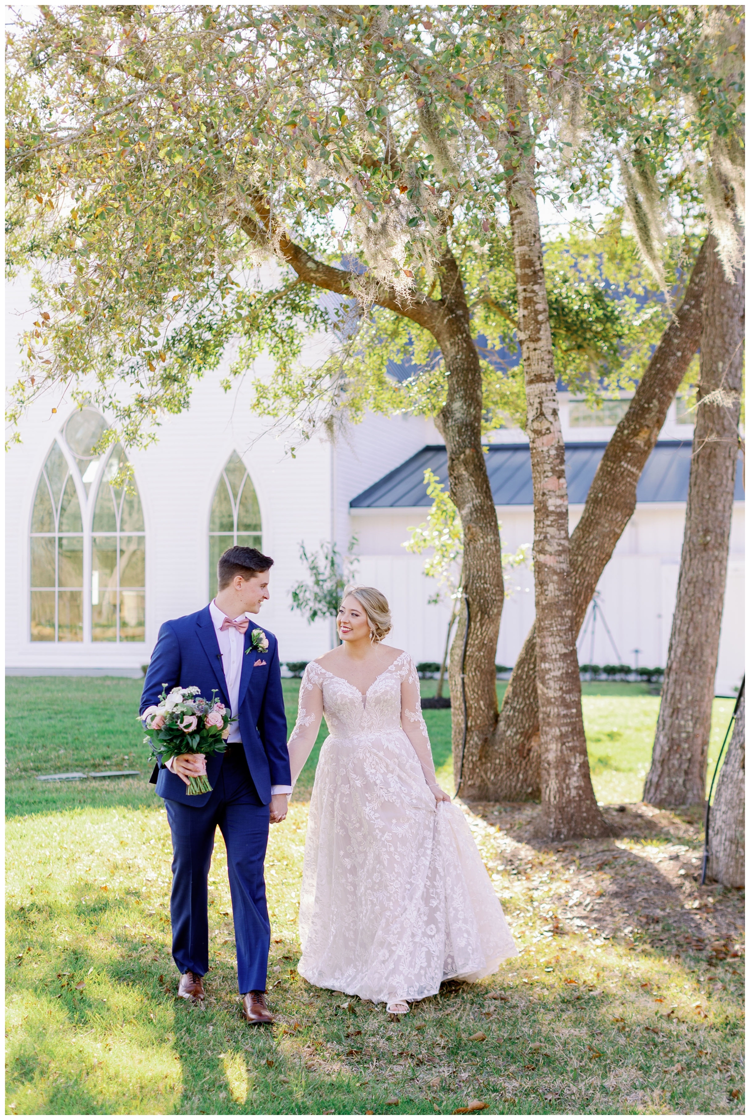 bride and groom holding hands and walking under trees at The Springs Wallisville Wedding venue