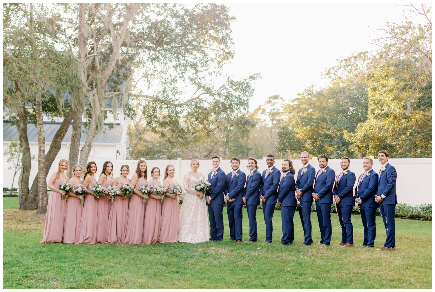 bridal party standing in a line in blue suits and blush dresses